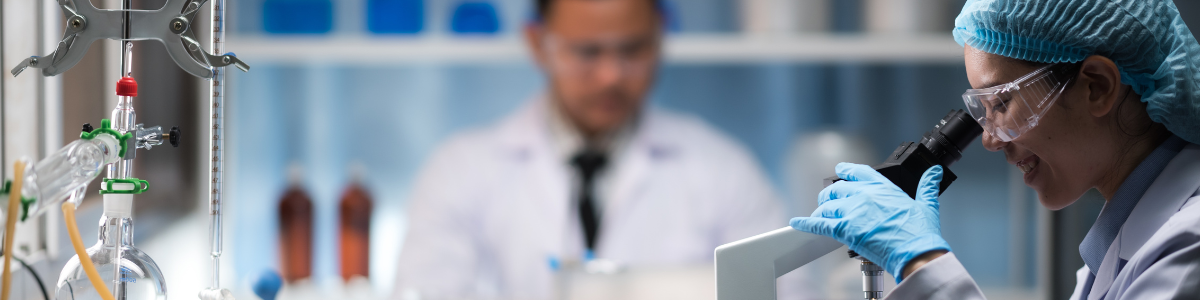A woman is looking through a microscope in a laboratory.