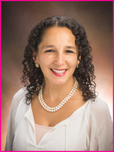 A woman with curly hair wearing a pearl necklace