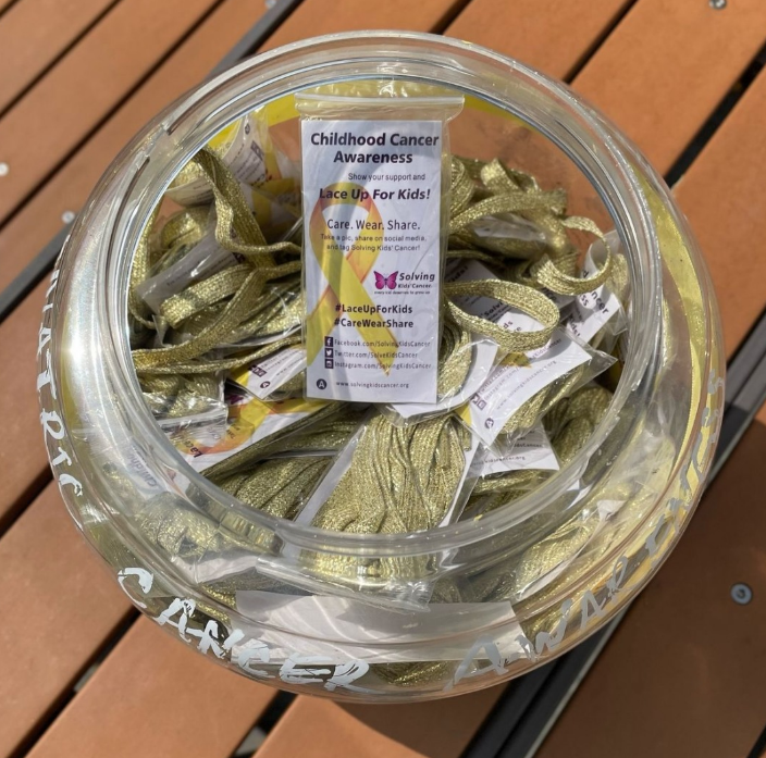 A glass jar filled with gold ribbons for childhood cancer awareness