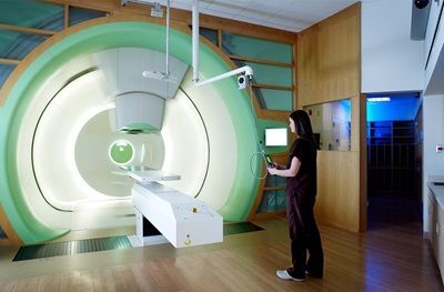 A woman is standing in front of an x-ray machine