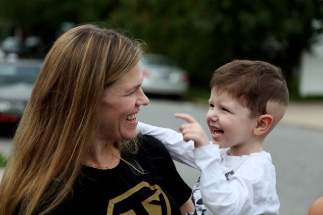 A woman is holding a child in her arms and pointing at him.
