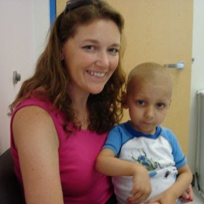 A woman in a pink shirt is holding a little boy in a blue shirt