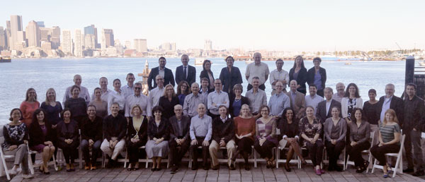 A large group of people are posing for a picture in front of a body of water.