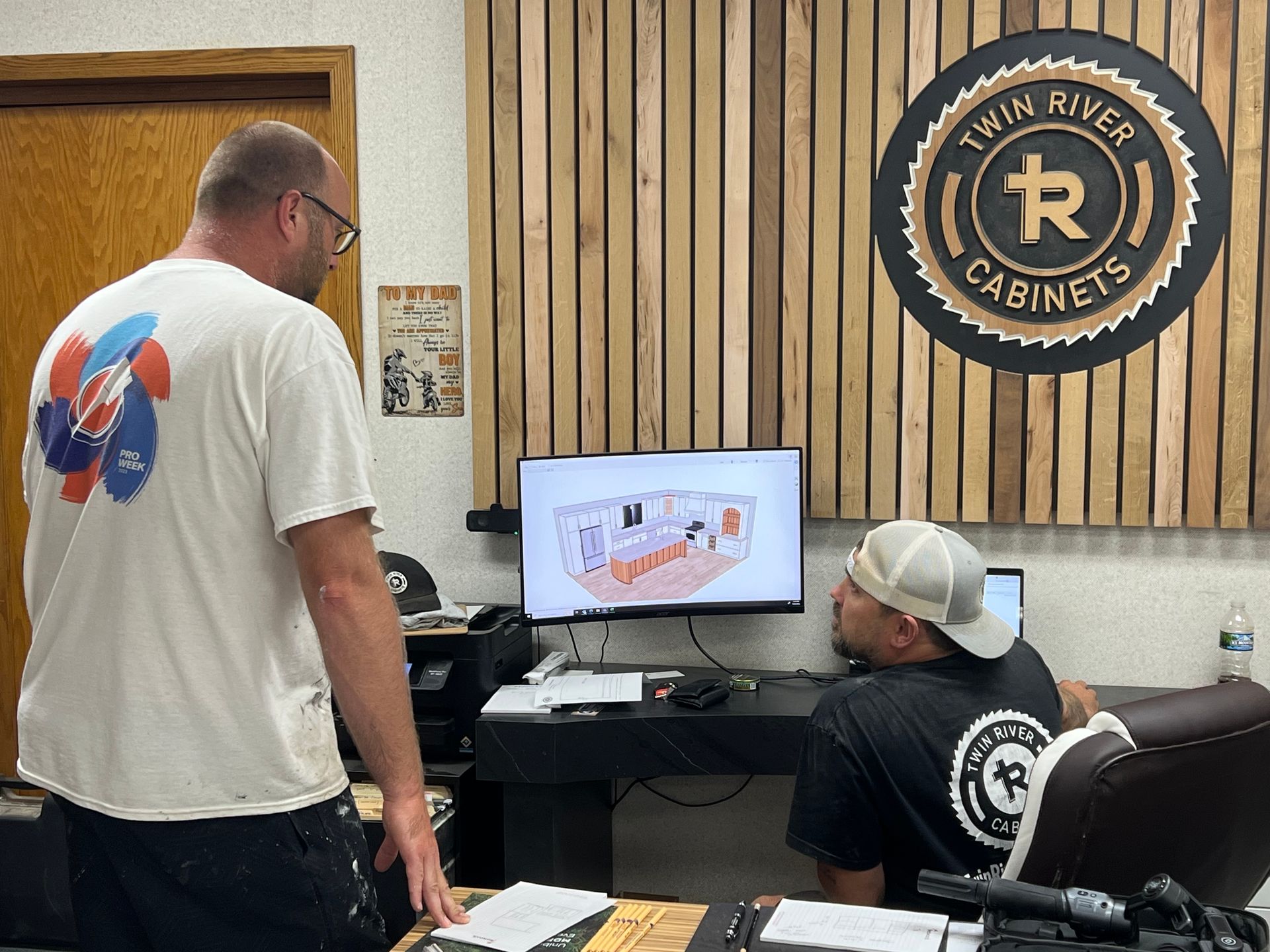 Two men are looking at a computer screen in an office.