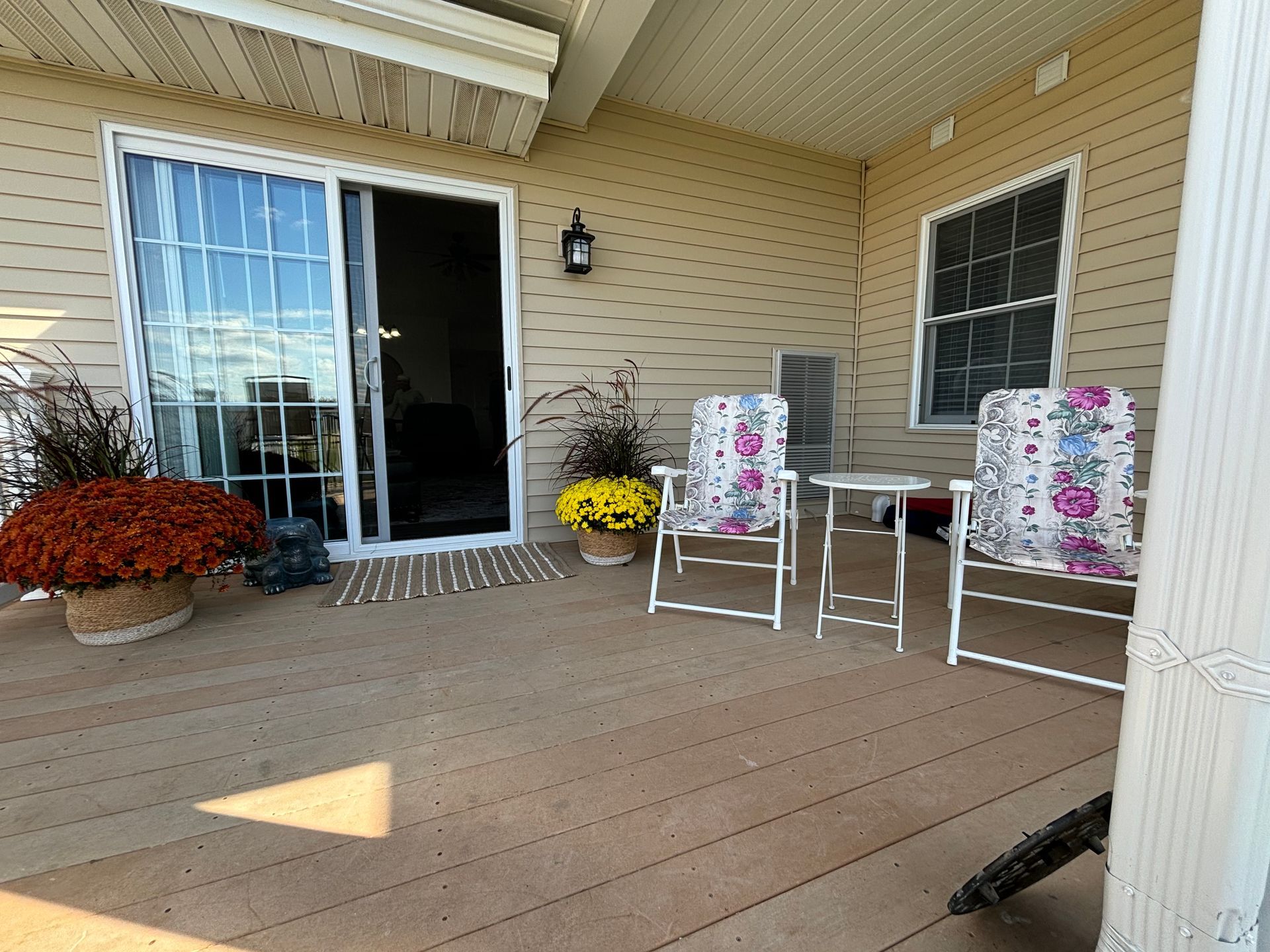 A deck with chairs , a table and flowers on it