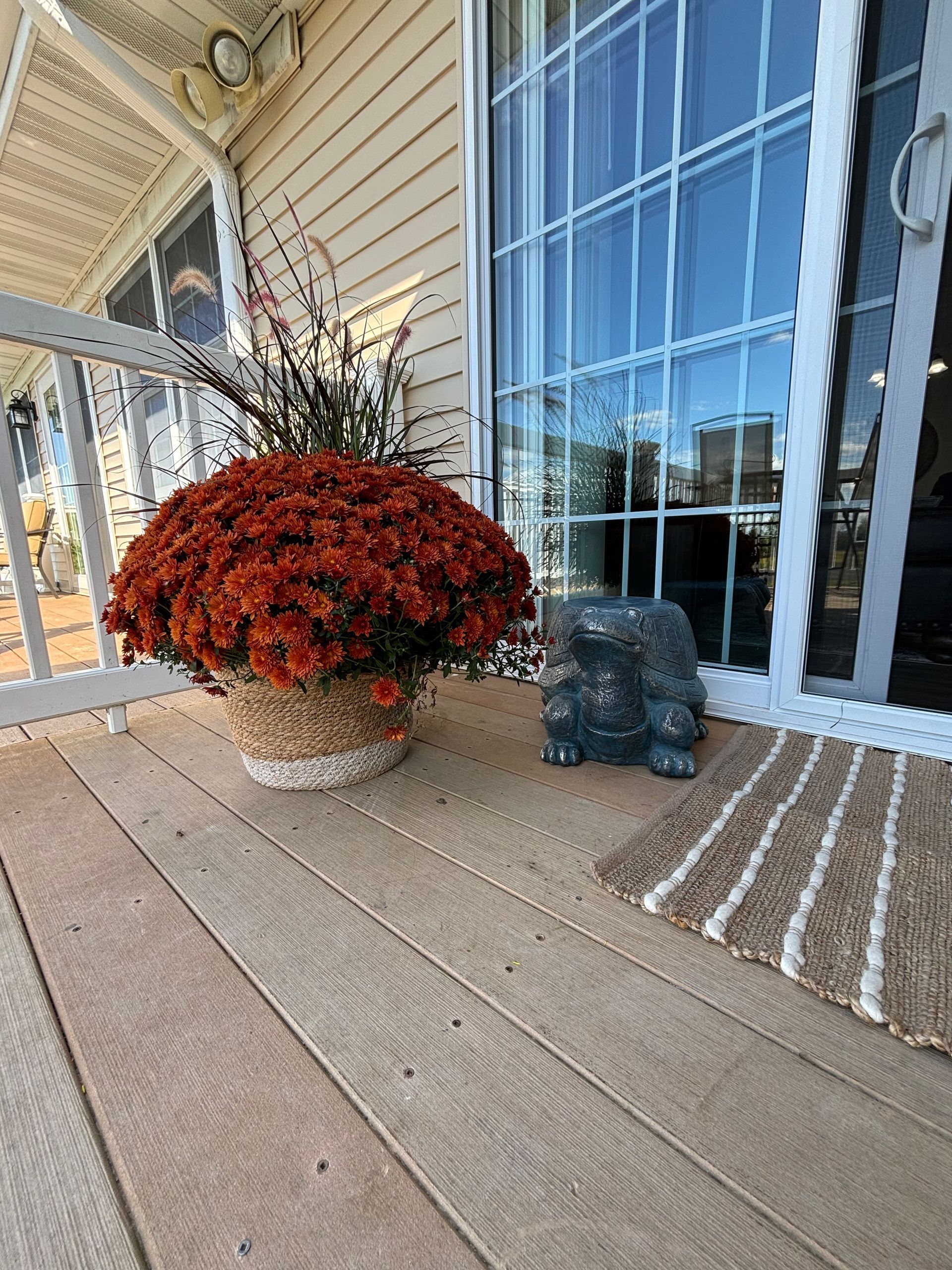 A turtle statue is sitting on a porch next to a pot of flowers.