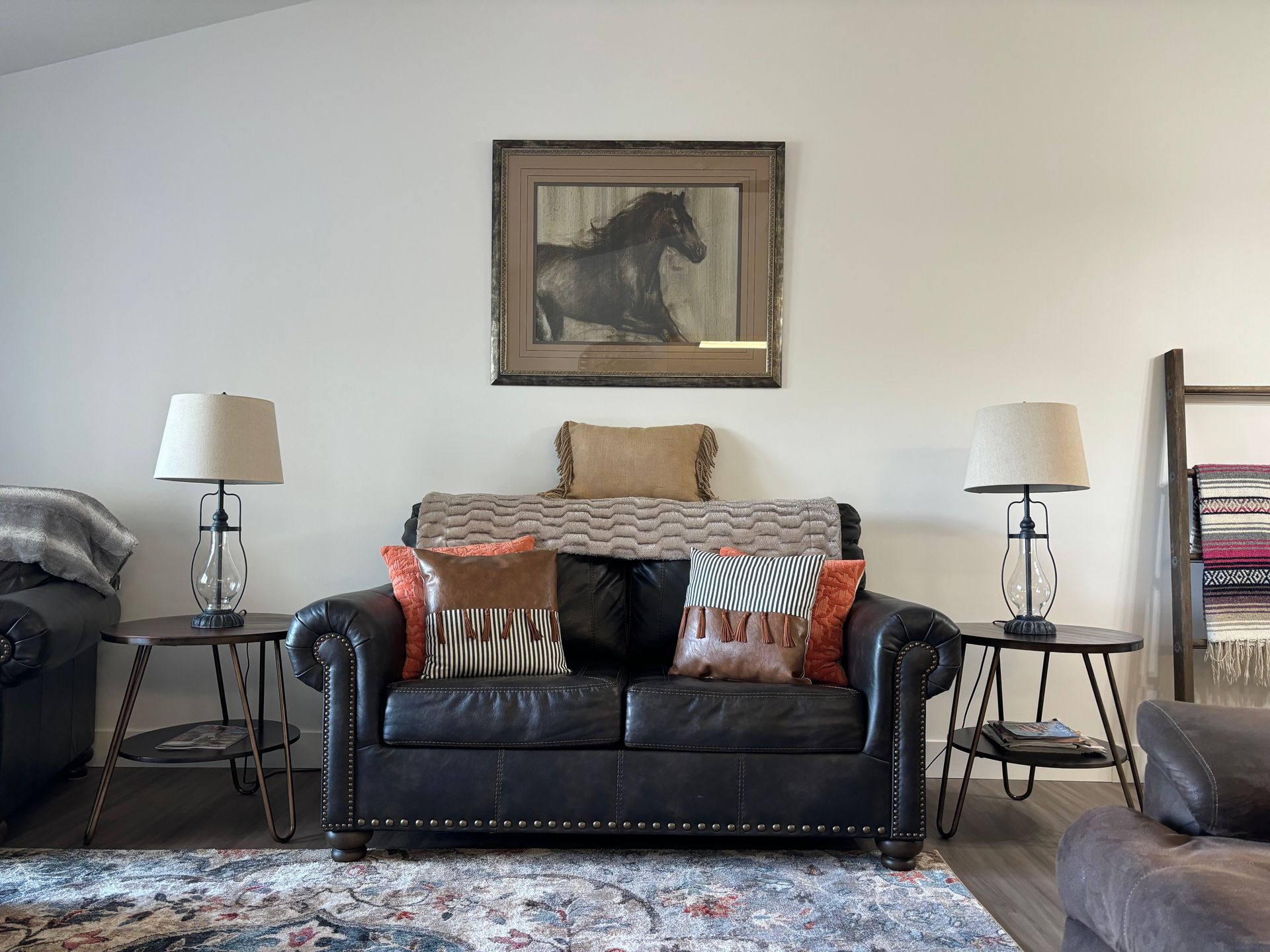 There is a picture of a horse on the wall above the couch in the living room.