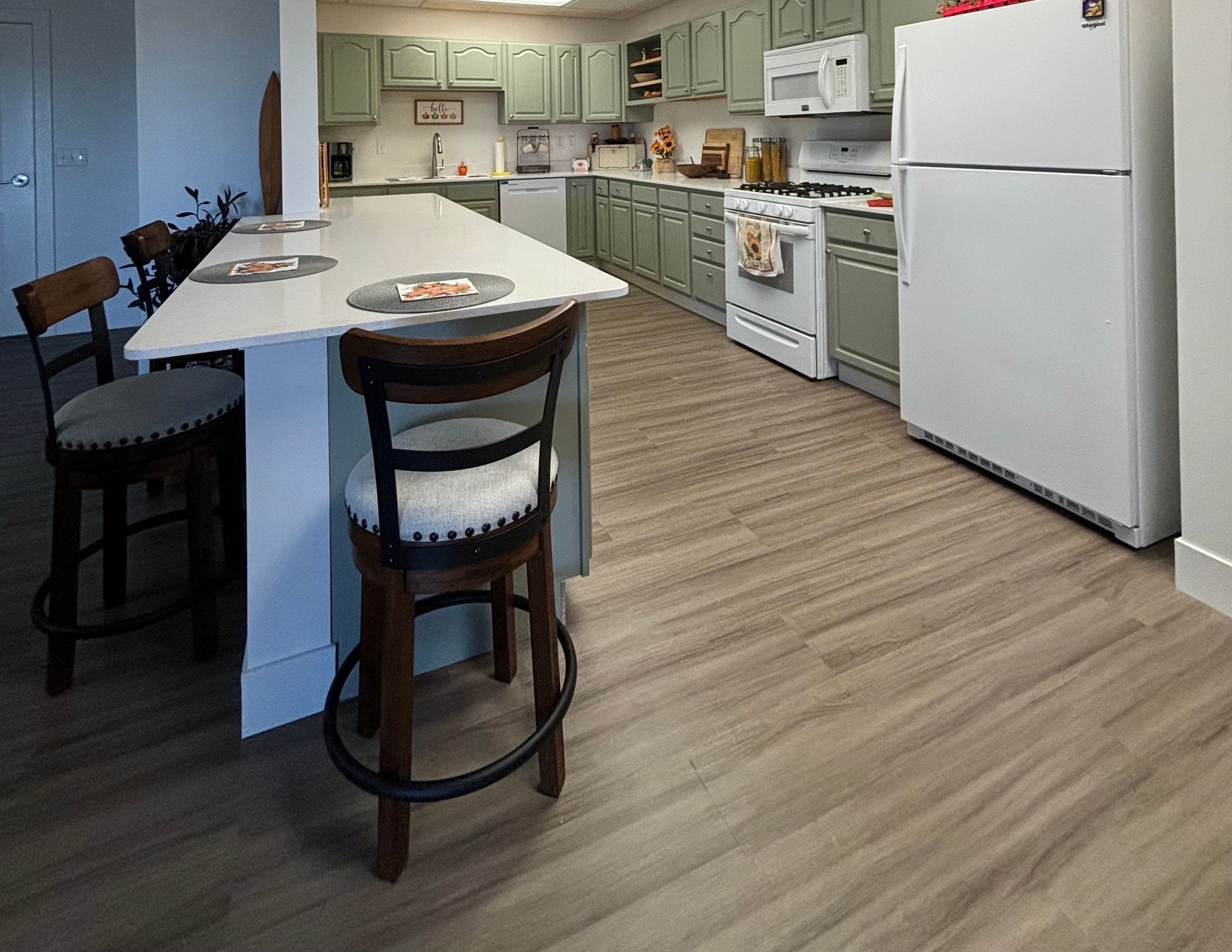A kitchen with a refrigerator , stove , sink , and chairs.