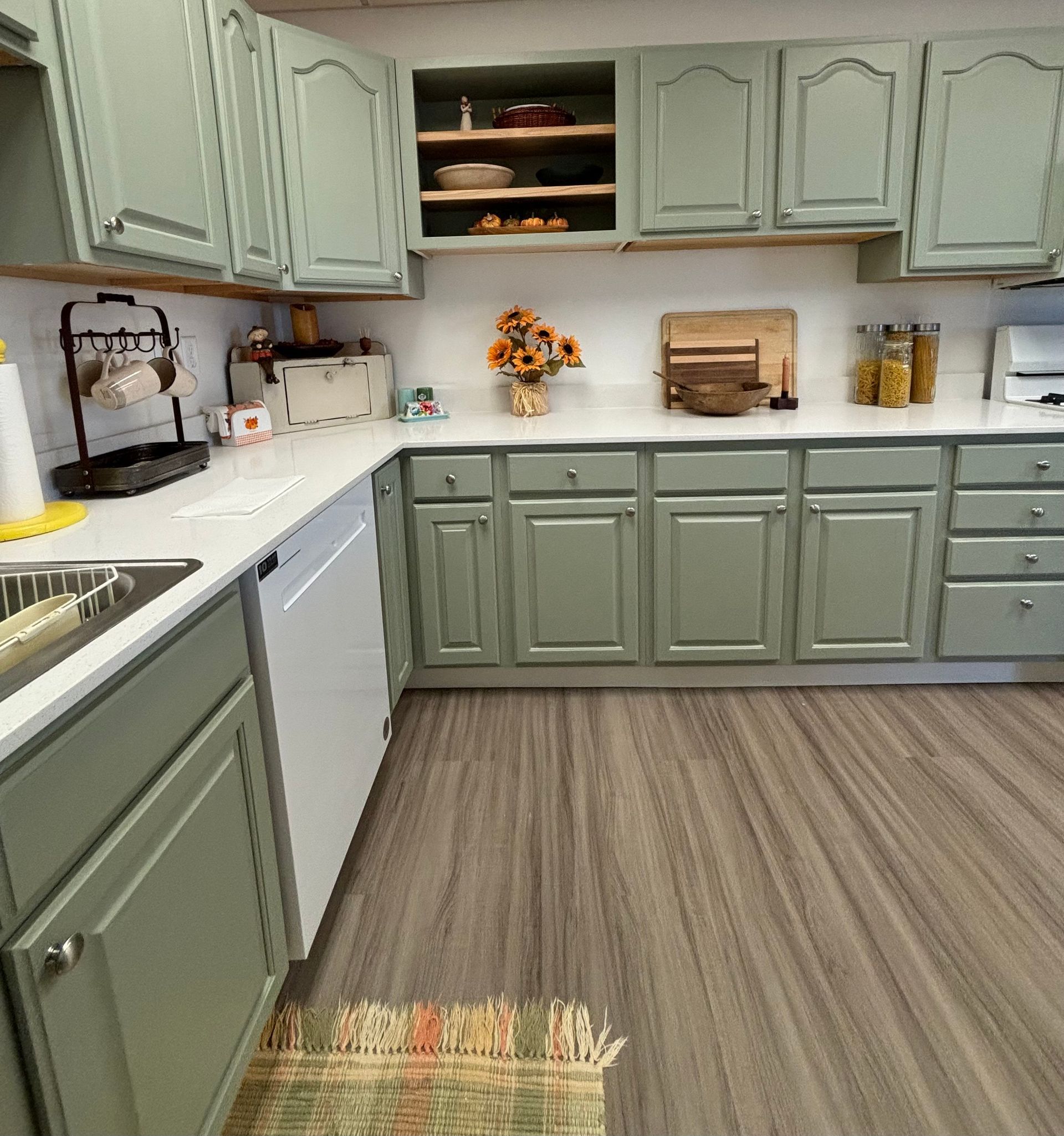 A kitchen with green cabinets and white counter tops