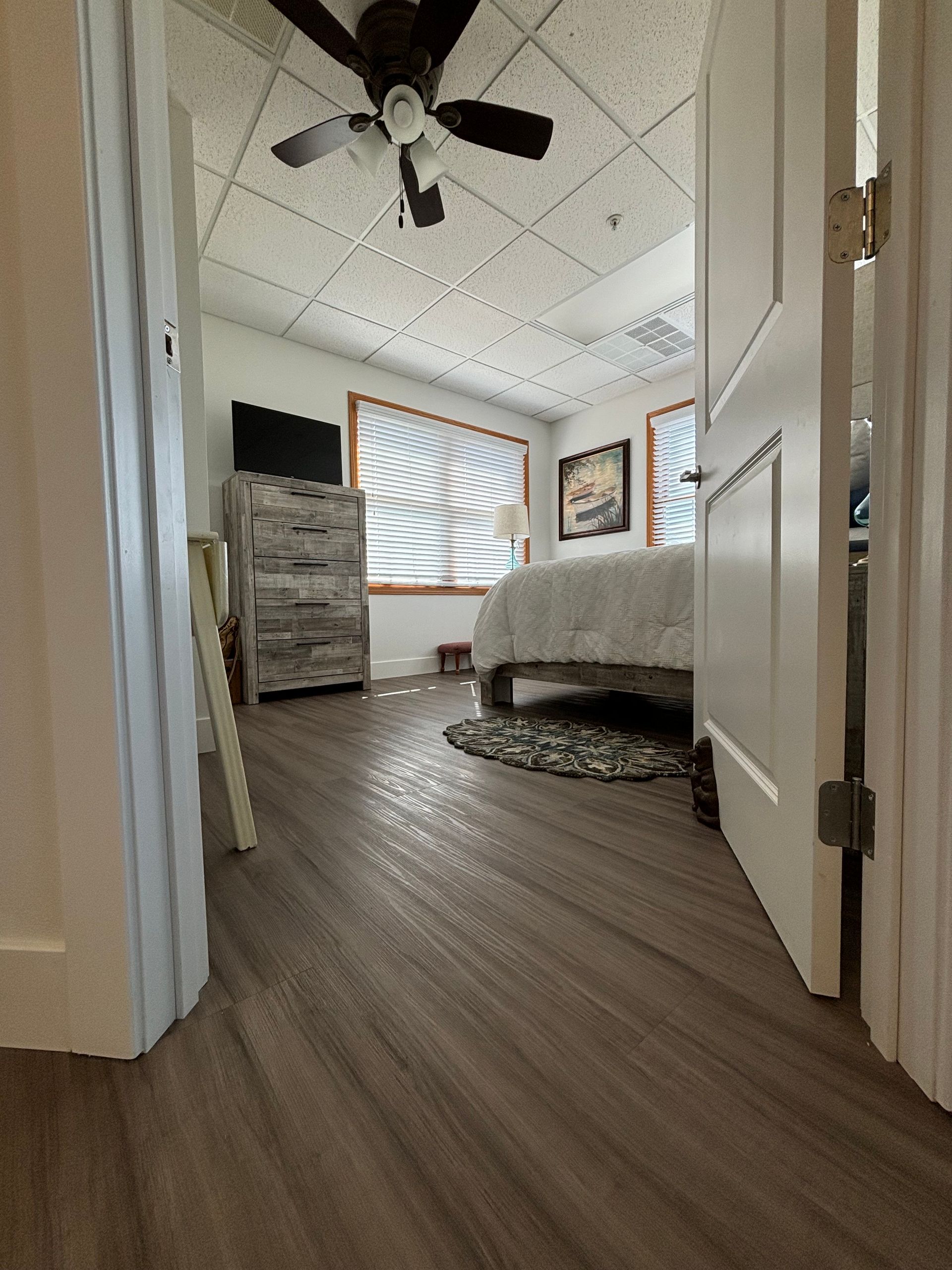 A bedroom with hardwood floors and a ceiling fan