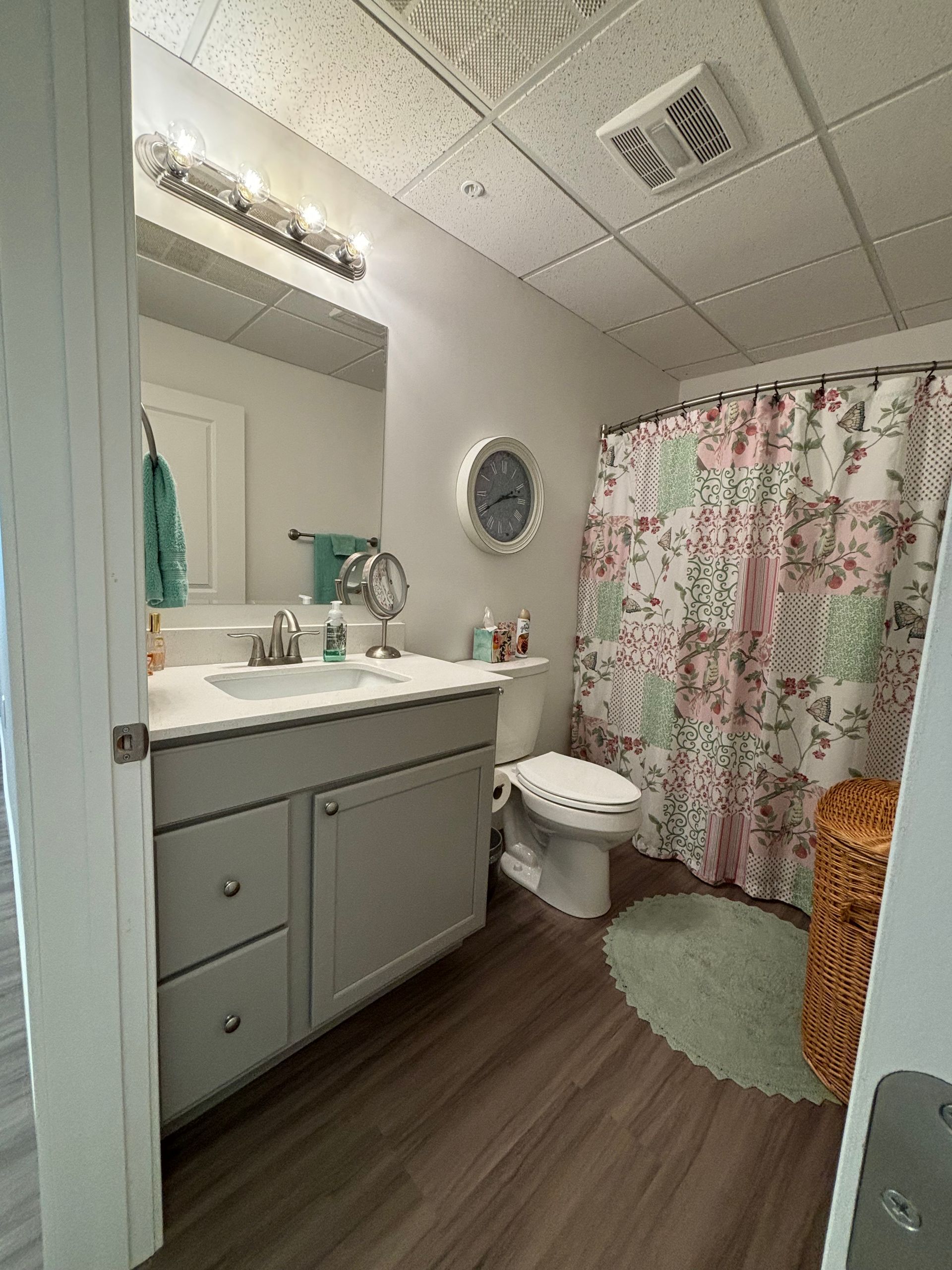 A bathroom with a sink , toilet , shower curtain and mirror.