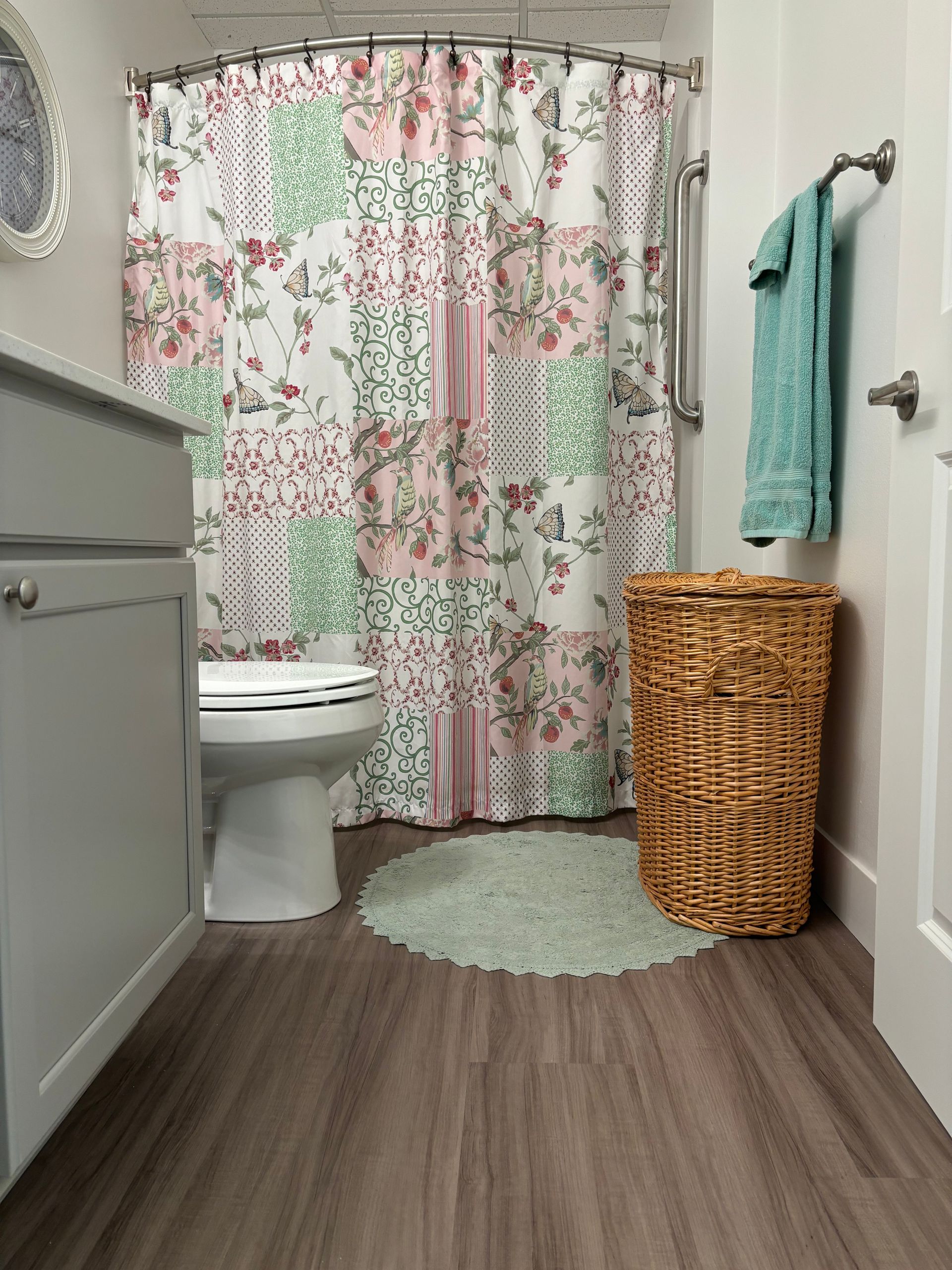 A bathroom with a toilet , sink , shower curtain and wicker basket.