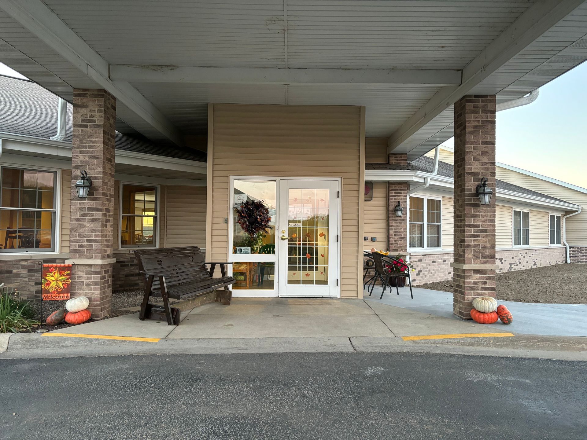 A large building with a porch and a bench in front of it.