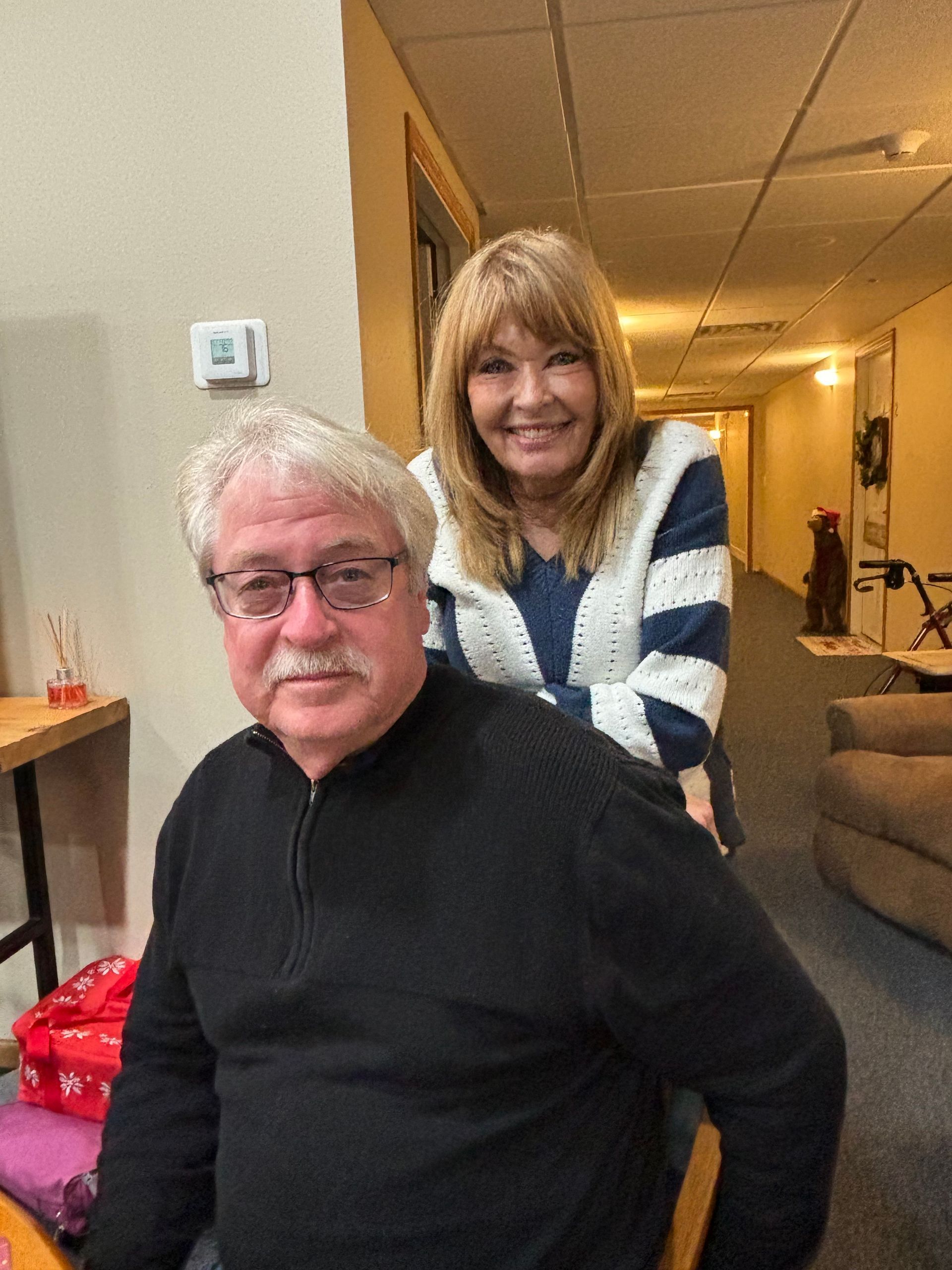 A woman is sitting on a man 's back in a hallway.