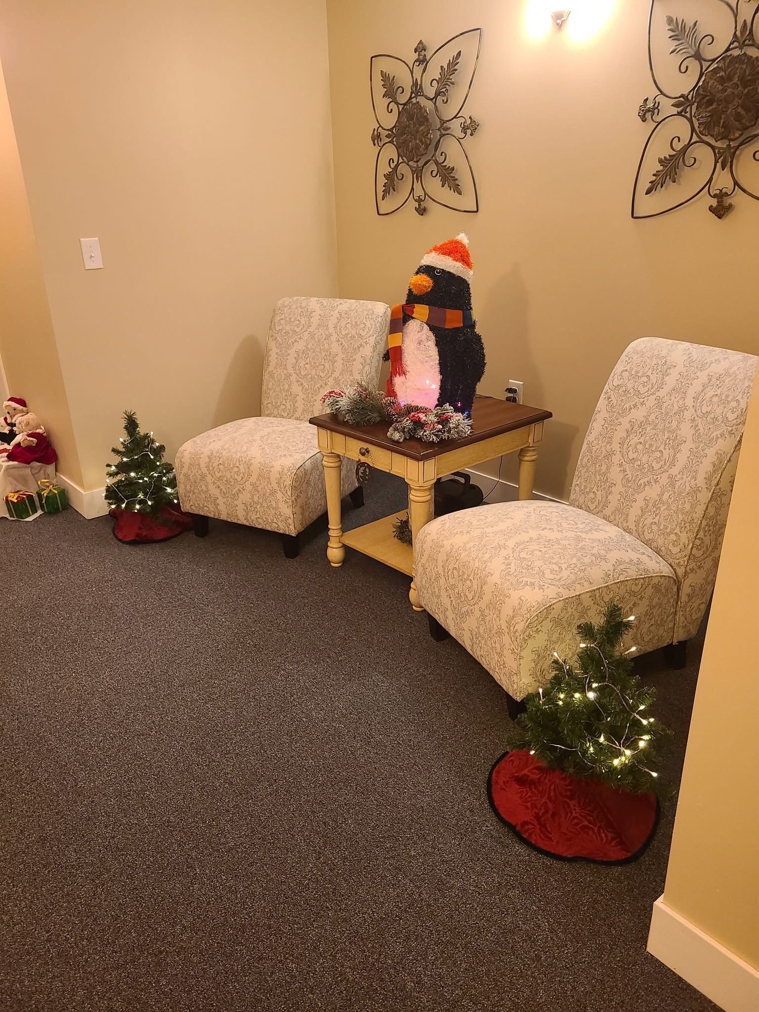 A waiting room decorated for christmas with two chairs and a table.