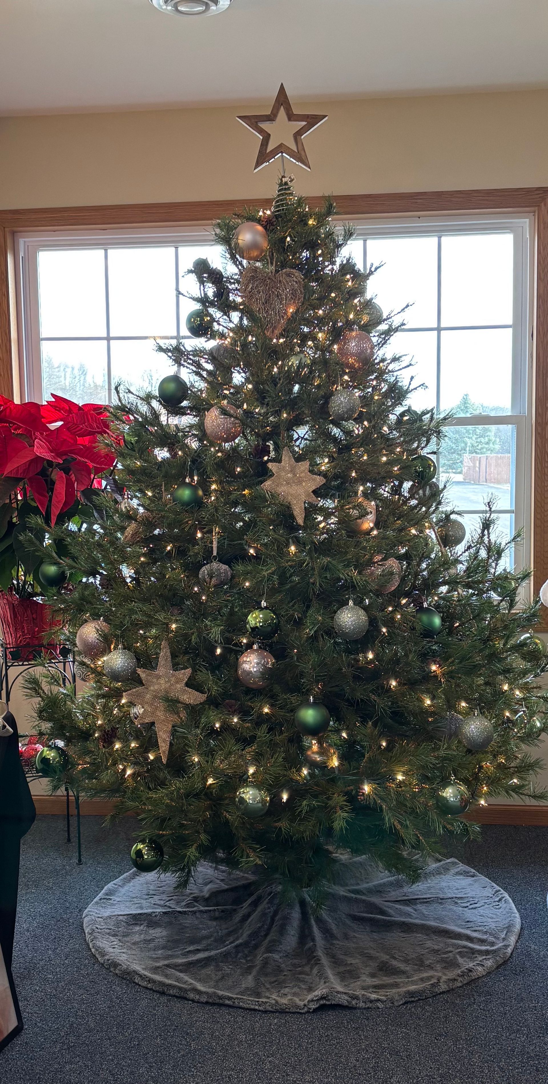 A christmas tree is sitting in front of a window in a living room.