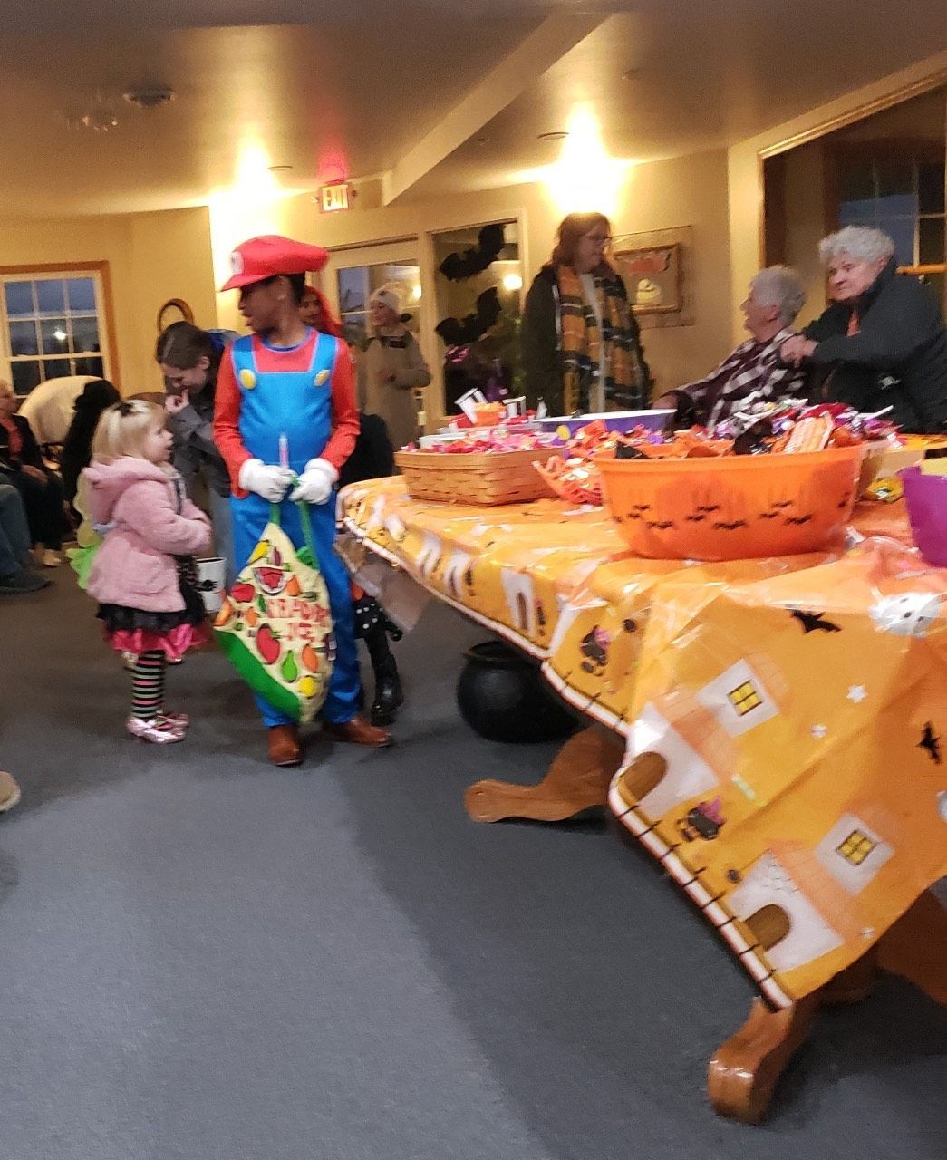 A man in a mario costume stands in front of a table full of candy