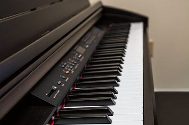 Black digital piano with open lid, keyboard in focus.
