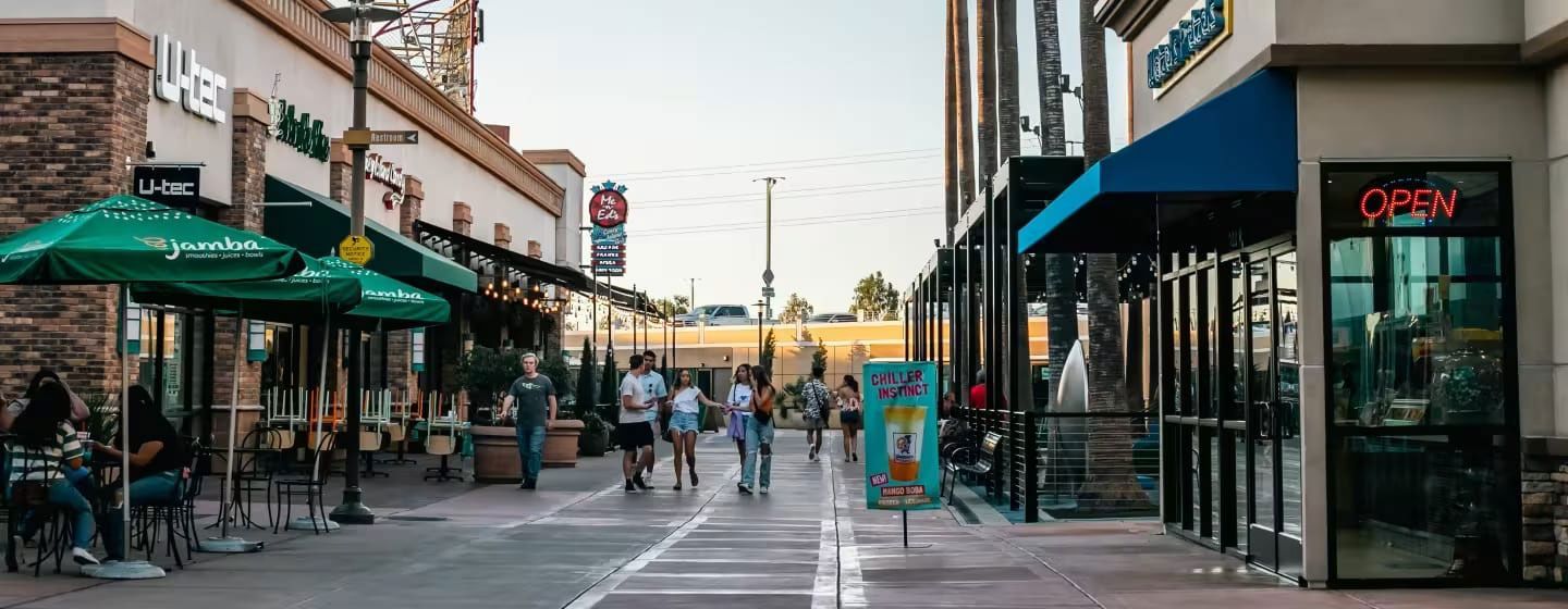 A group of people are walking down a sidewalk in front of a shopping mall.