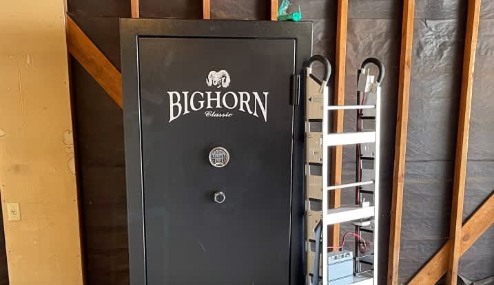 A bighorn safe is sitting in a garage next to a ladder.