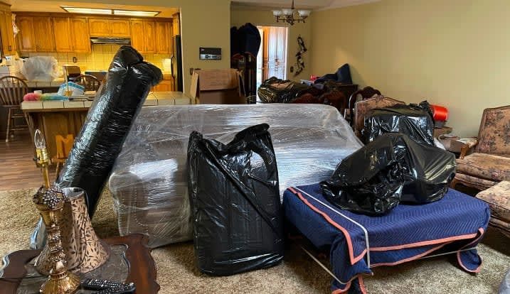 A living room filled with furniture and bags wrapped in plastic.