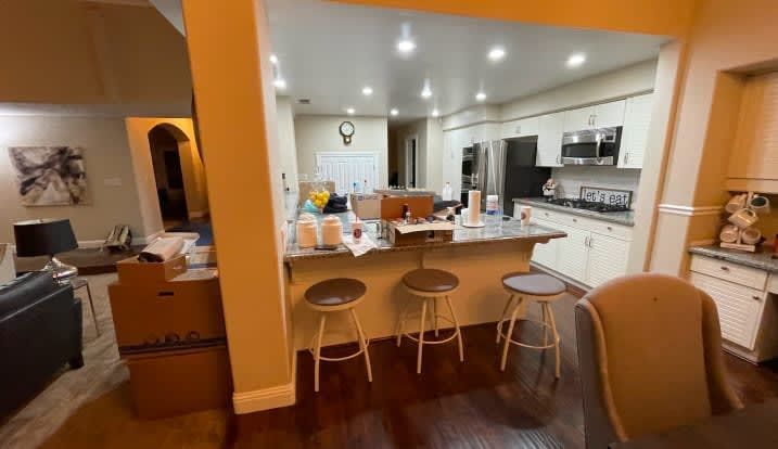 A kitchen with a bar and stools in a house.