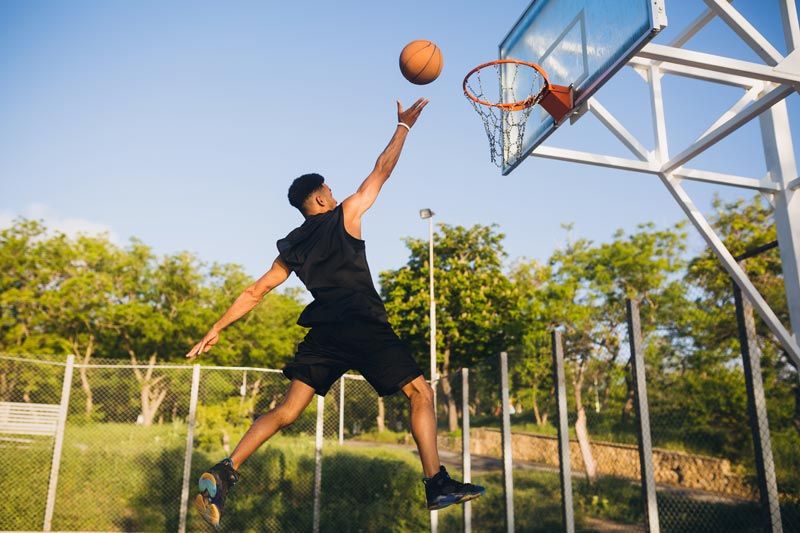 A man is jumping in the air to dunk a basketball into a hoop.