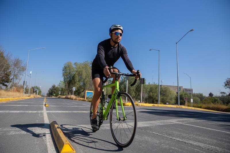 A man is riding a green bicycle down a street.