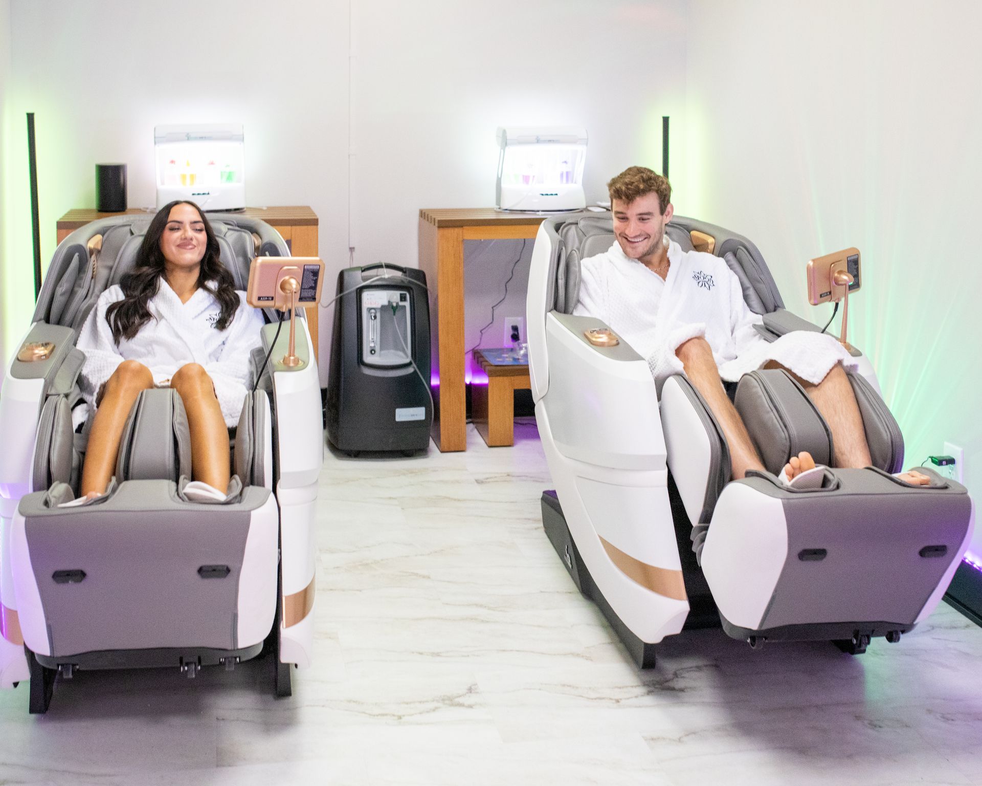 Woman relaxed in a massage chair, eyes closed, in a room with orange and white walls.