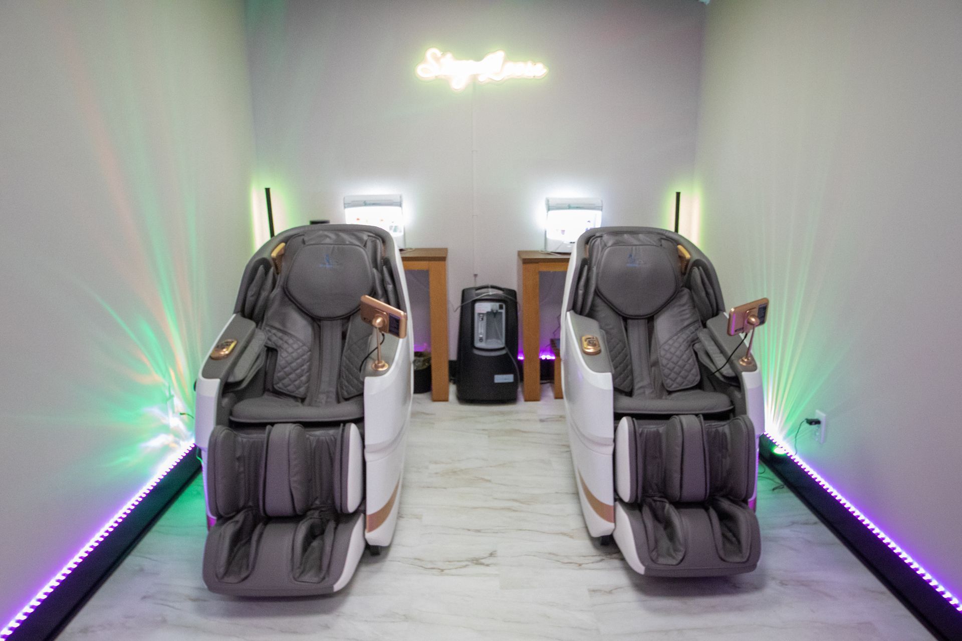 Woman relaxed in a massage chair, eyes closed, in a room with orange and white walls.