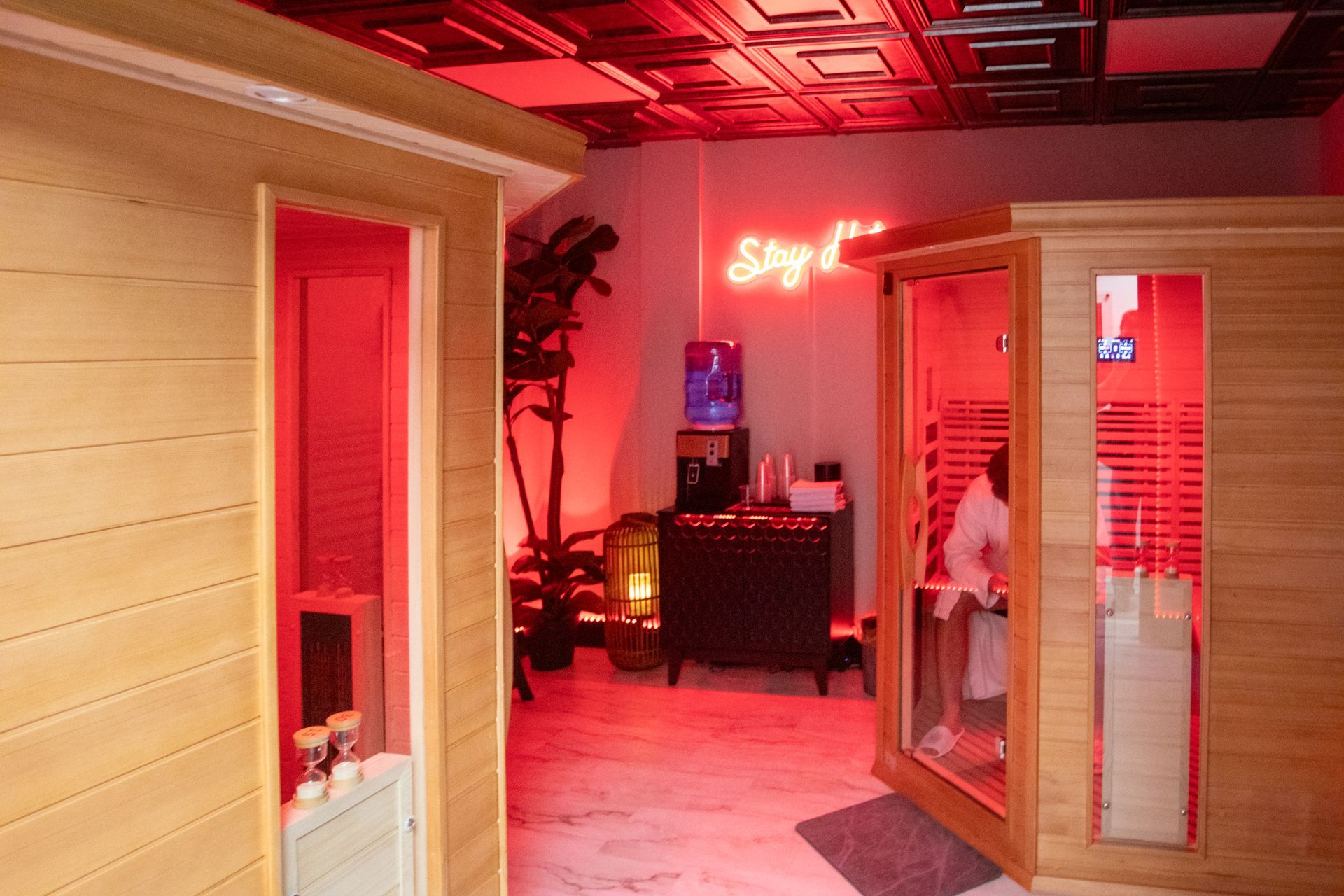 A couple relaxing in a wooden sauna, bathed in red light.