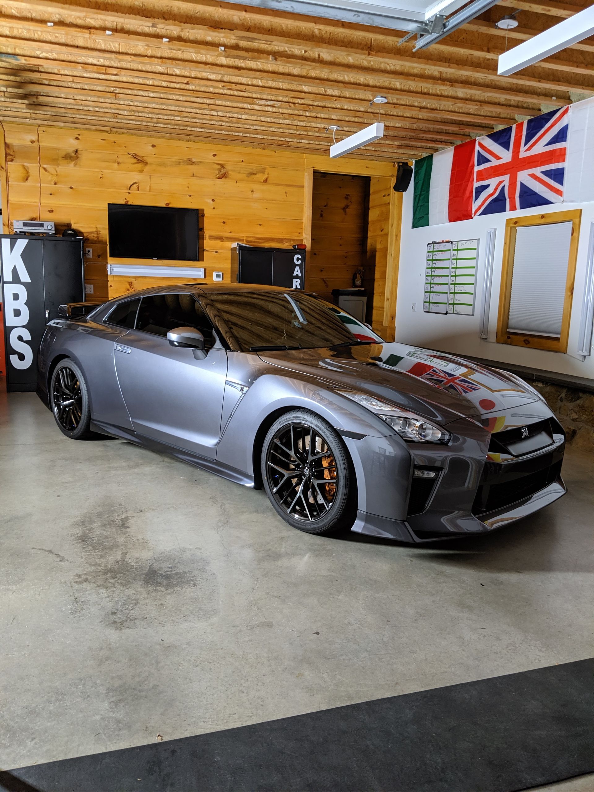 Gray sports car parked in a wooden garage with a British flag on the wall