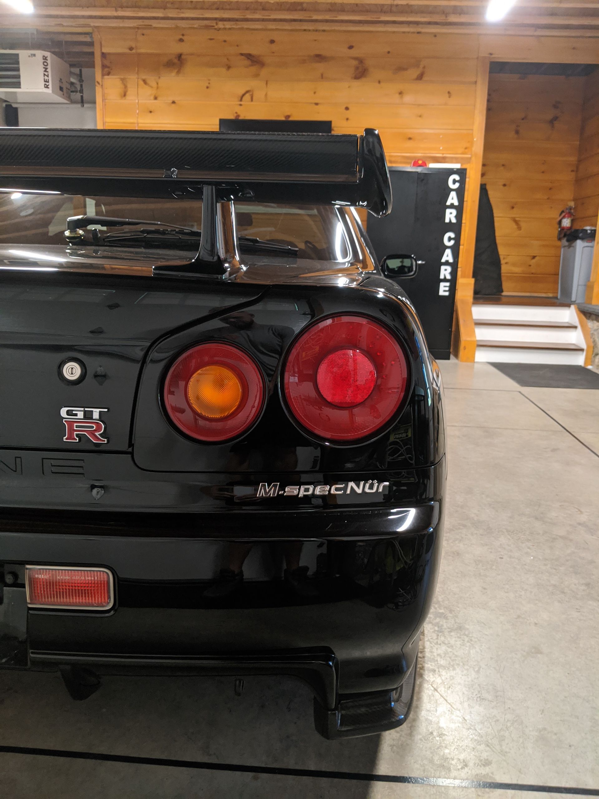 Rear view of a black Nissan Skyline GT-R with round taillights in a garage.
