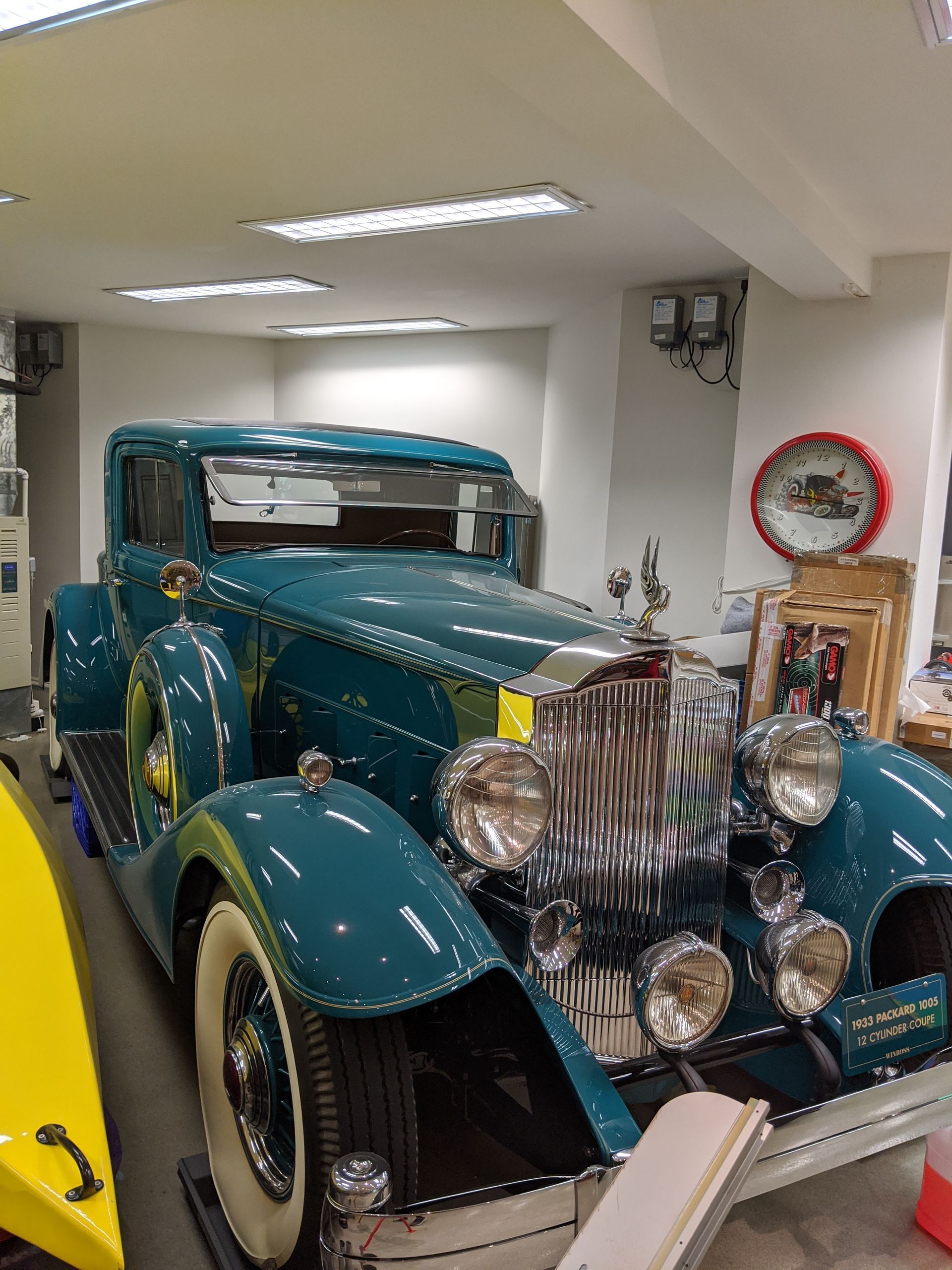 Vintage teal classic car displayed indoors in a showroom, with chrome details and whitewall tires