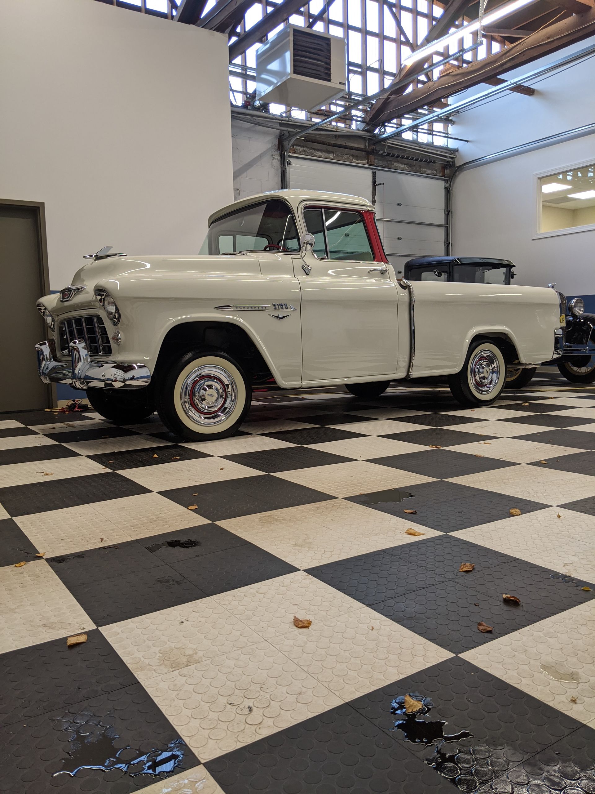 Classic white vintage car in a showroom with a black-and-white checkered floor.