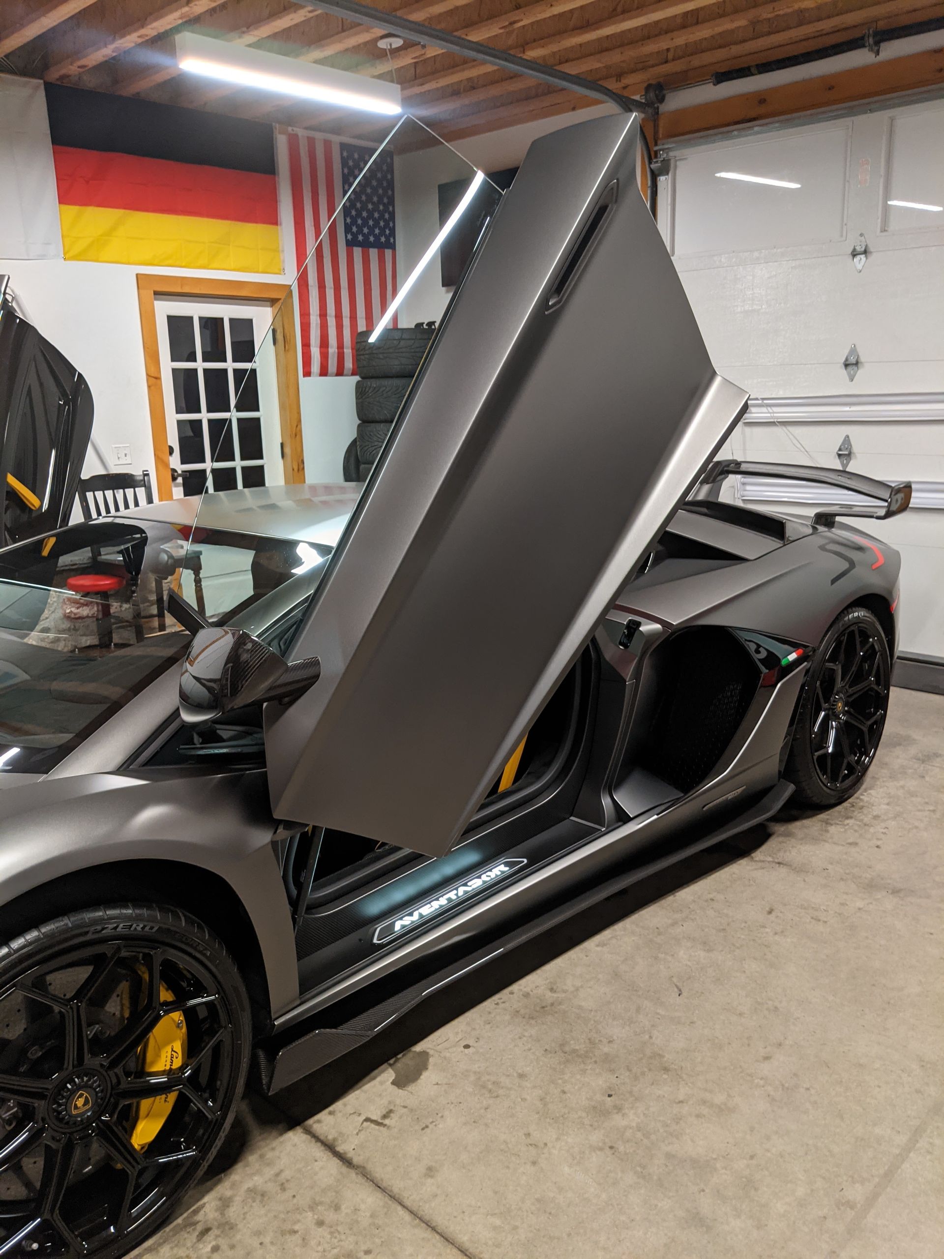Black sports car in a garage with its driver-side scissor door raised open