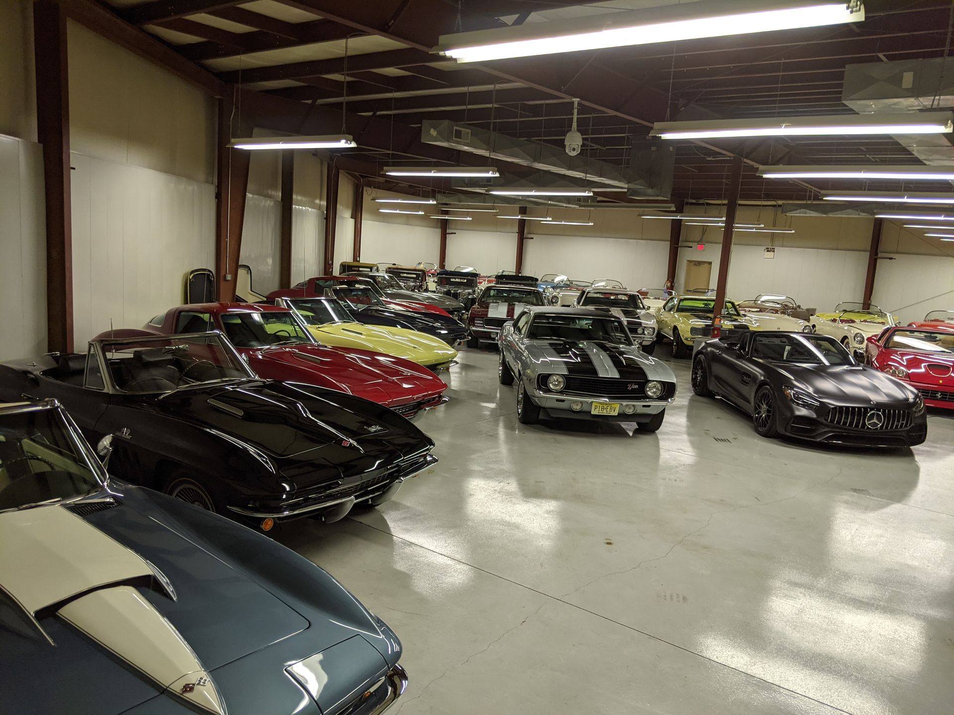 Classic sports cars parked inside a large warehouse showroom.
