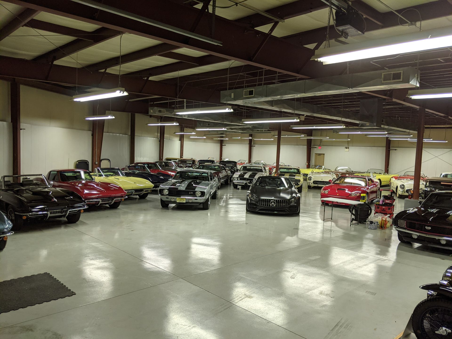 Indoor car showroom with several parked sports cars under bright overhead lights