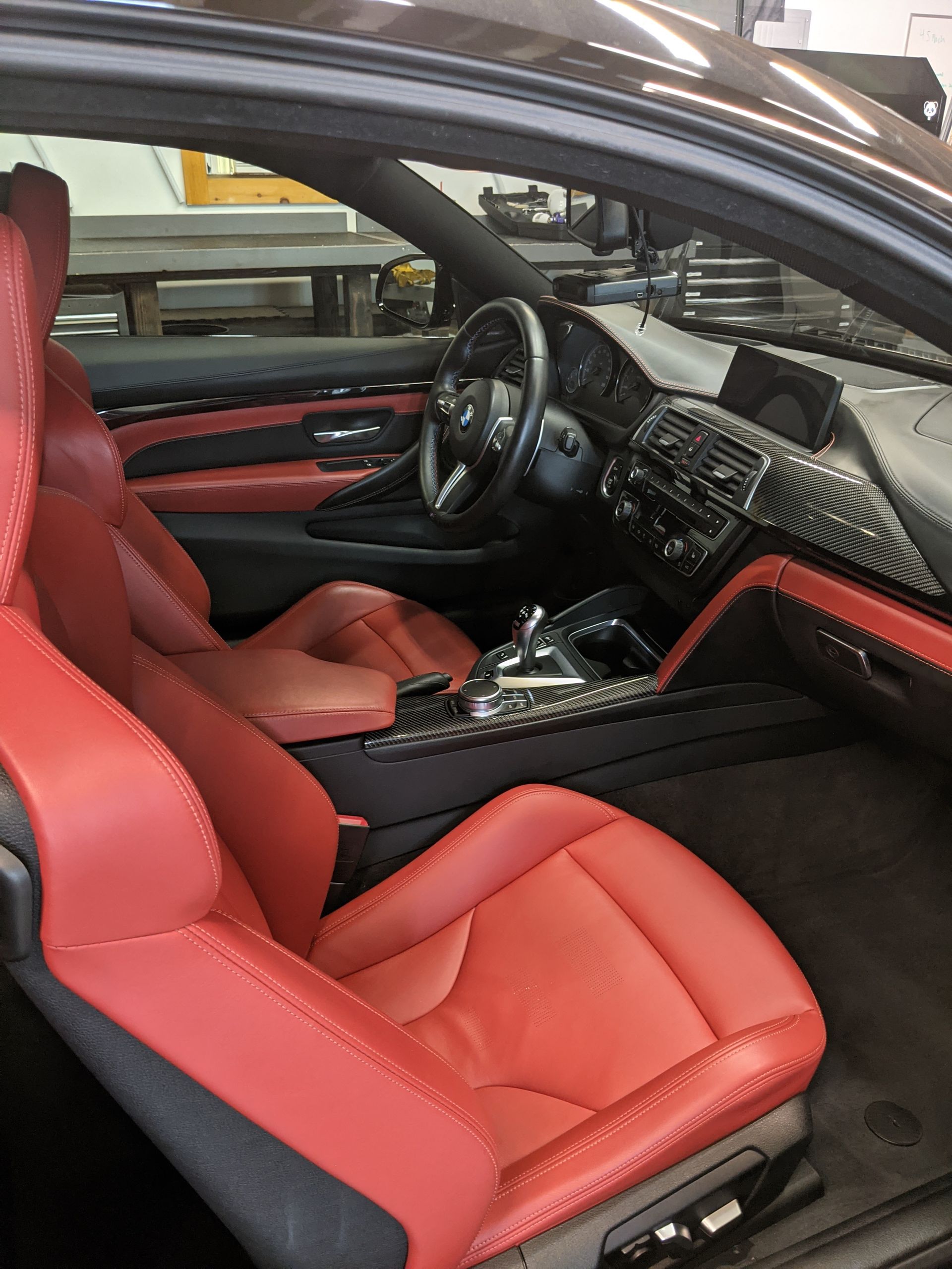 Red leather car interior with black dashboard and steering wheel, viewed from the passenger side