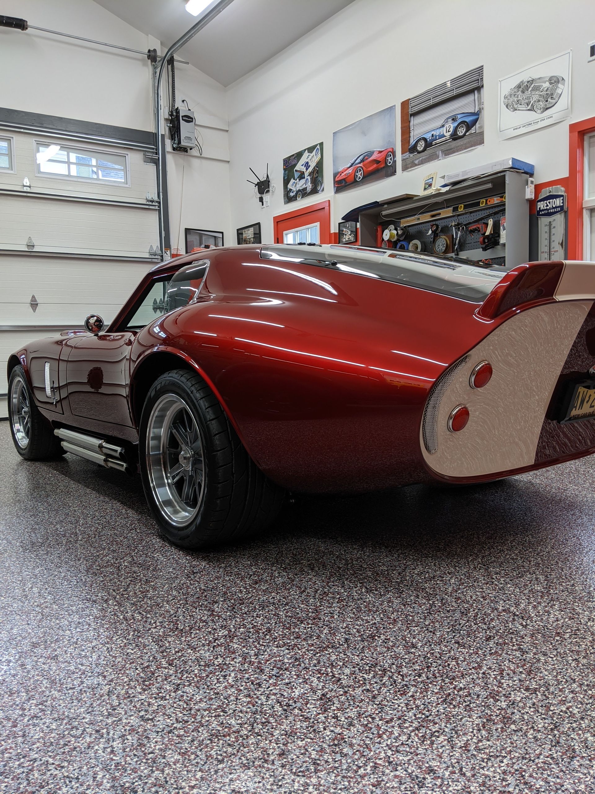Red classic sports car in a garage, rear three-quarter view, with glossy paint and racing-style wheels