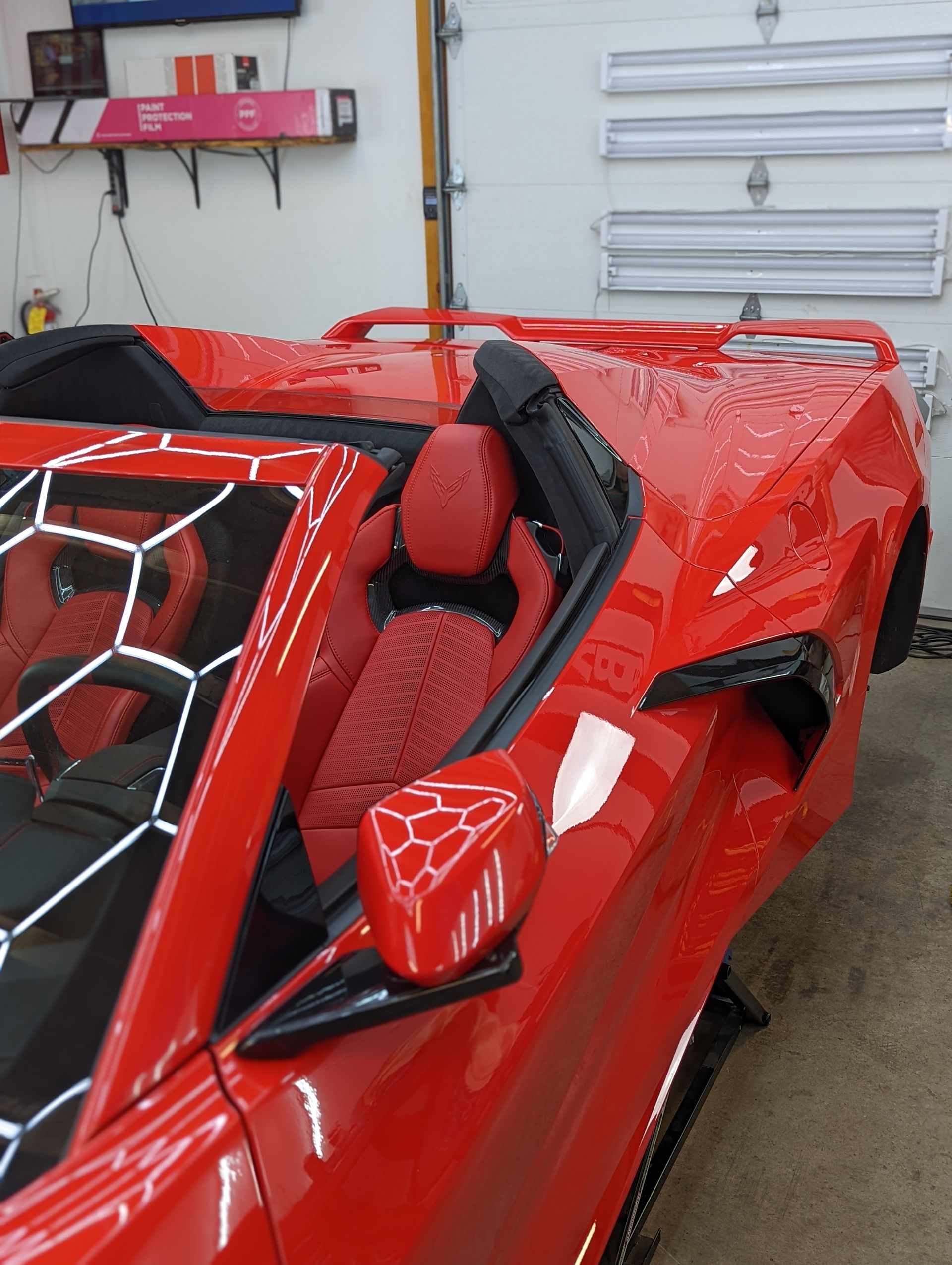Red convertible sports car with black and red interior in a garage.