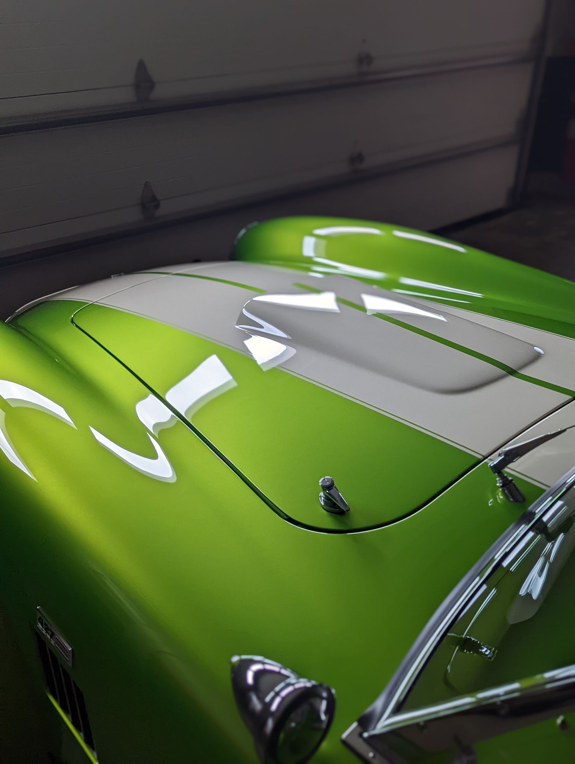 Bright green classic car hood with gray stripe, shown in a garage