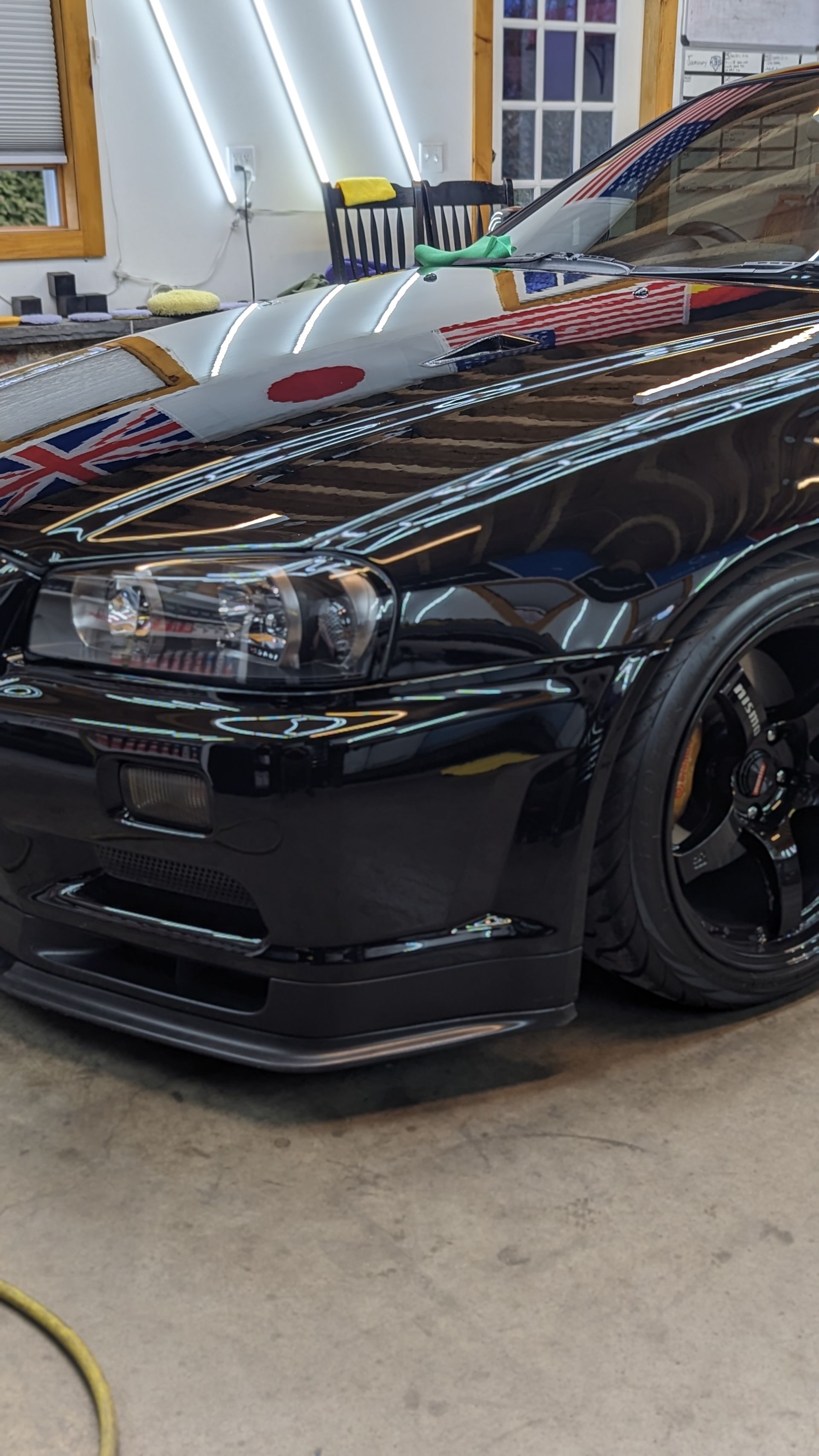 Black modified sports car with reflective hood parked indoors in a garage