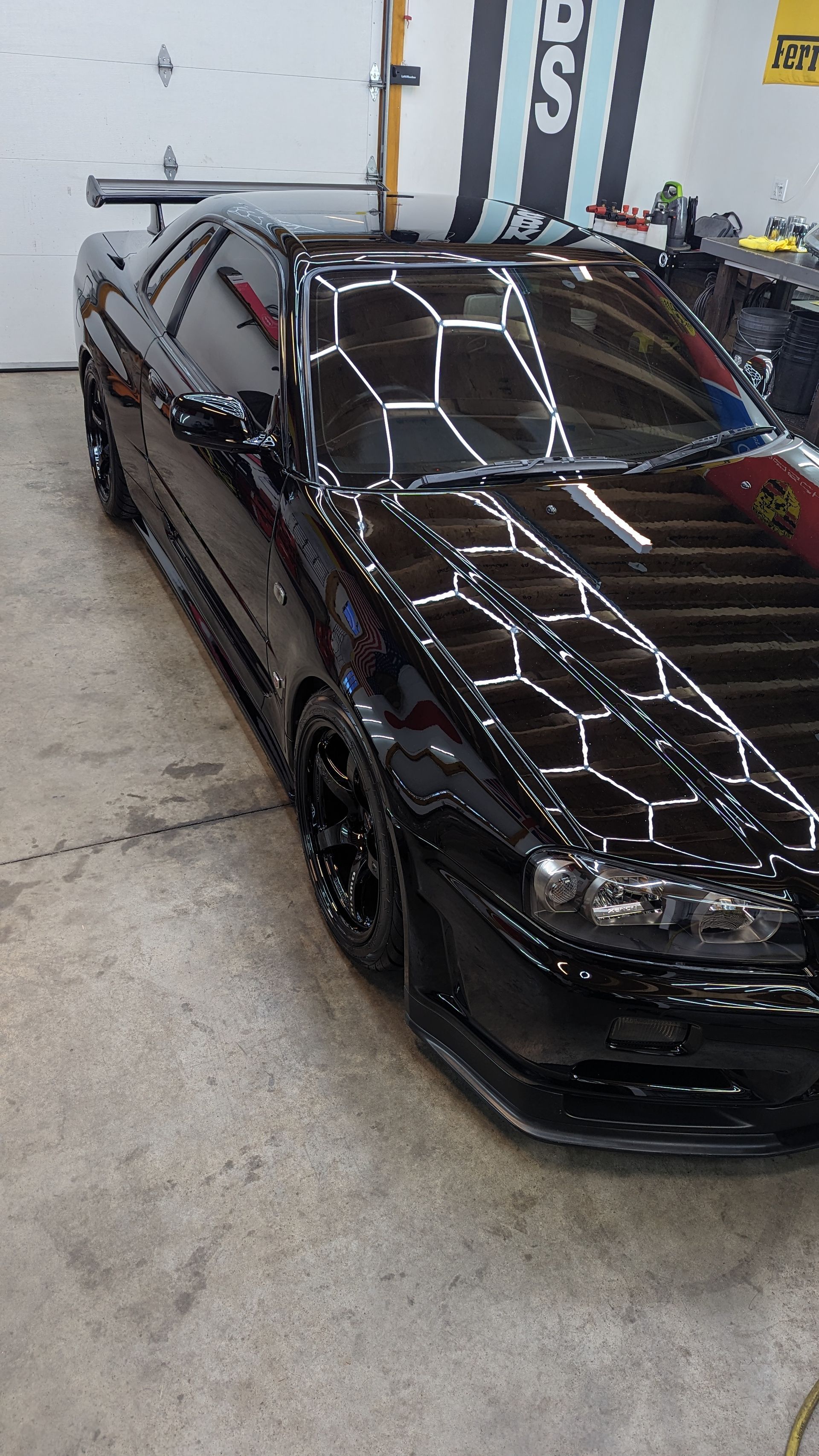 Black sports sedan in a garage, viewed from the front-left side.