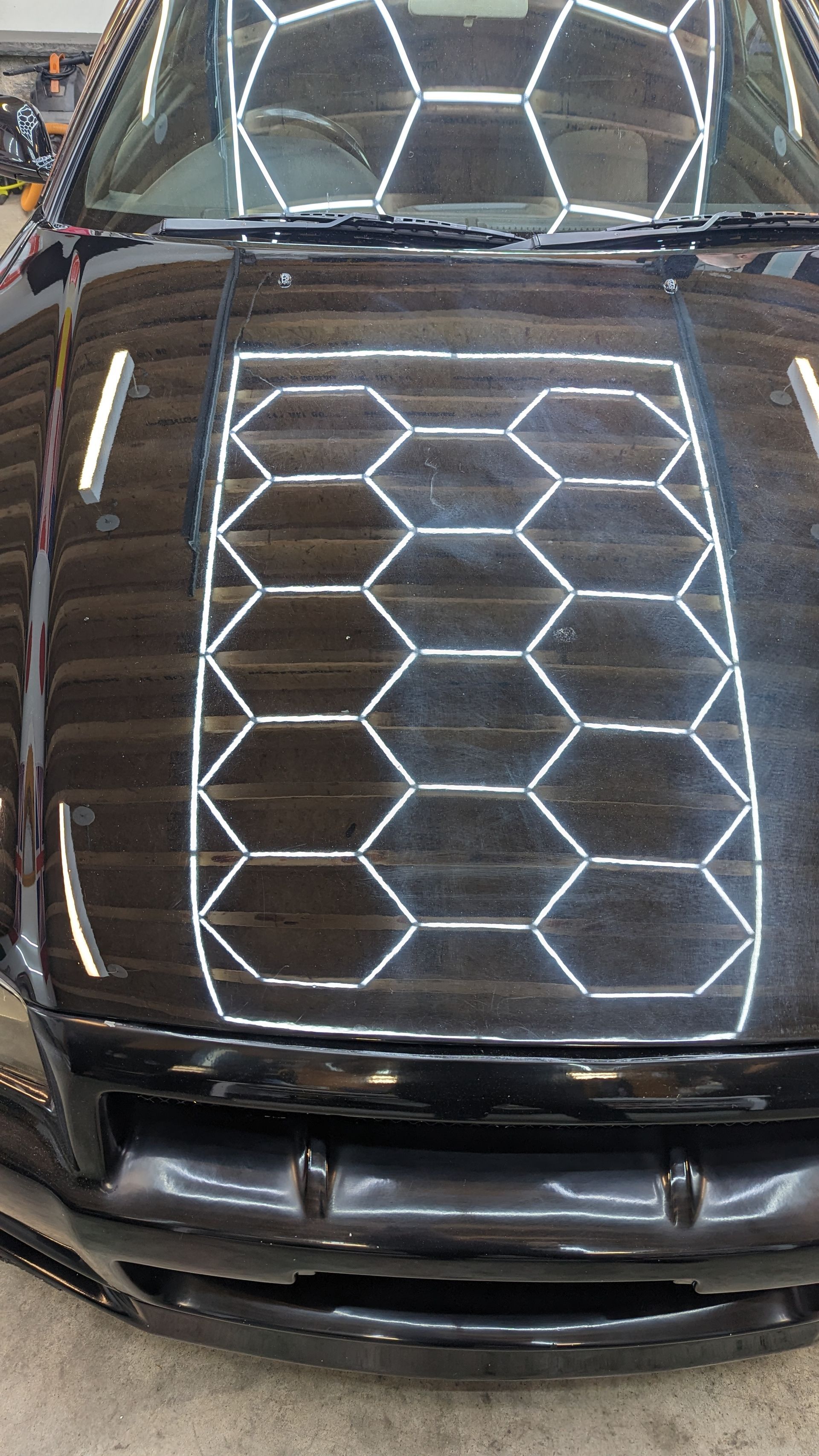 Black car hood and windshield covered with white hexagonal line patterns