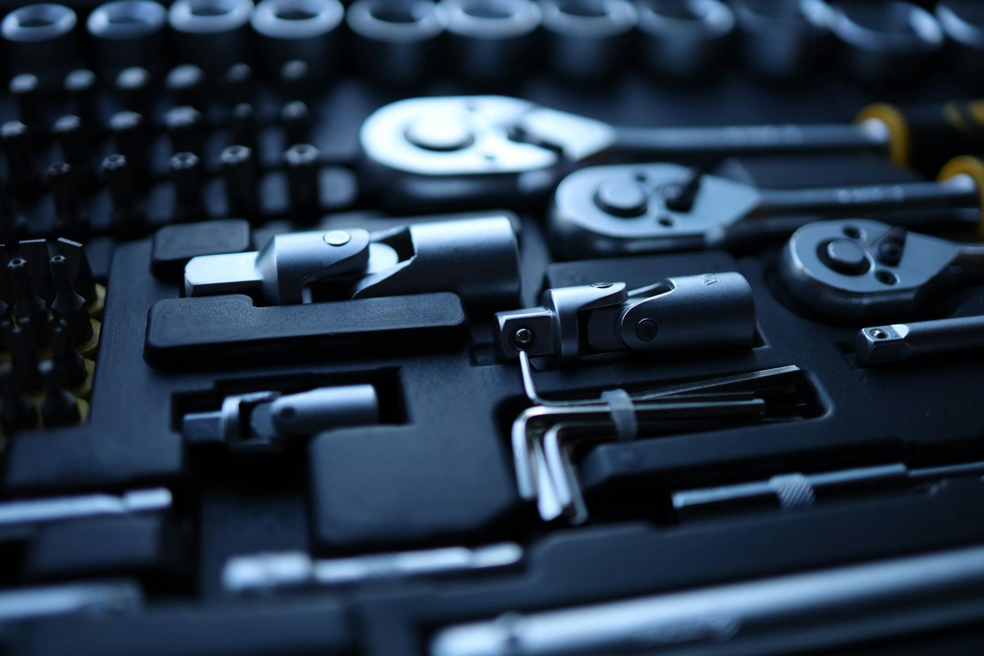 A top-down view of a socket wrench set in a black molded organizer case, featuring various ratchets and tool attachments.