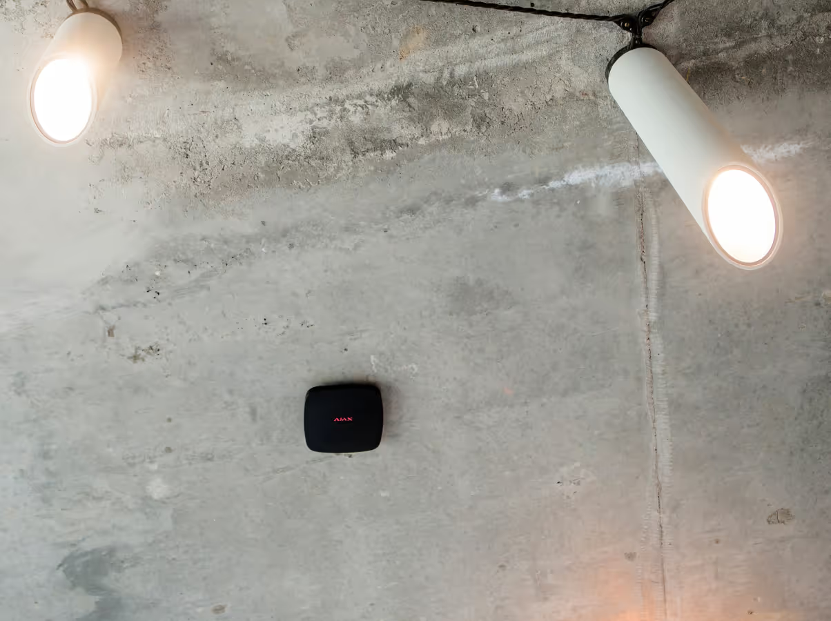 A concrete ceiling featuring two white cylindrical spotlight fixtures and a small black square motion sensor — Cussler NQ in Proserpine, QLD
