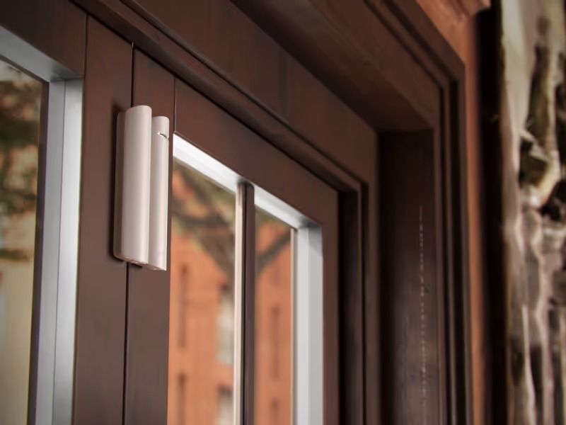 White Door Sensor Attached to a Brown Wooden Door Frame, Near a Window — Cussler NQ in Cannonvale, QLD