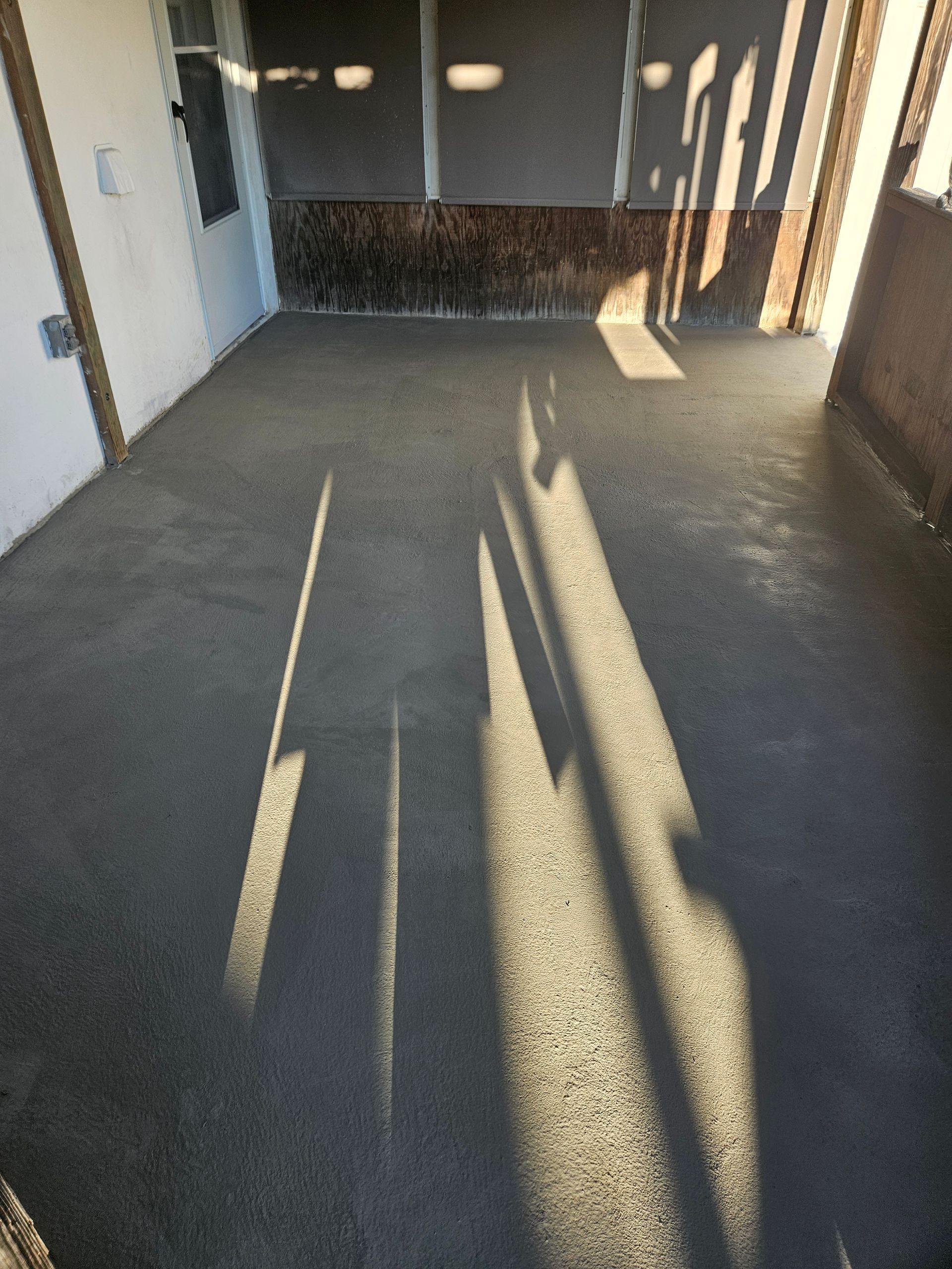 A view of a newly poured concrete patio floor, showing textures and long shadows cast by the setting sun.