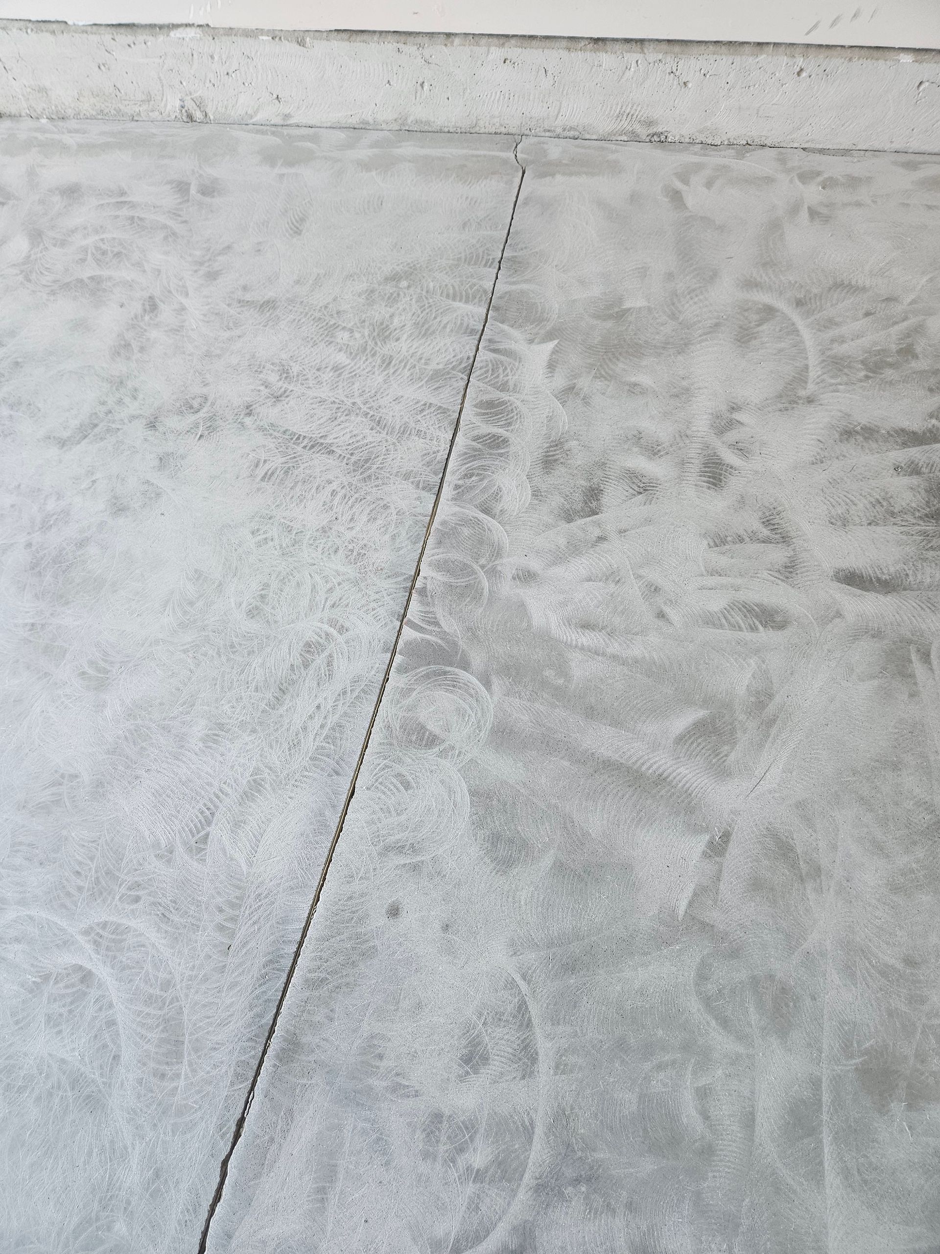 A concrete garage floor with a visible, straight crack running from the wall toward the center.